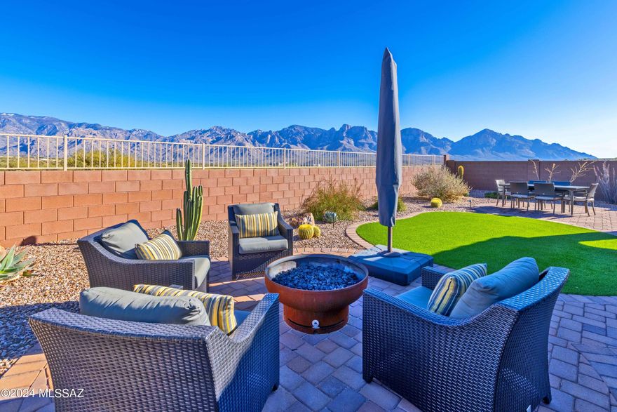 Discover the ideal blend of tasteful elegance & Majestic Mtn VIEWS in this meticulously cared for 3Bd, Den, 2.5-bth 2021 built home. Boasting an array of amenities, including a full 3-car garage, this residence is nestled on an oversized homesite backing the captivating Honeybee Canyon Wash & Entire Catalina Mountain Range in your sights. Step inside the Salerno Floorplan with Wood Plank Tile flooring throughout (NO CARPET) for style and durability. This home's interior paint has been thoughtfully upgraded with quality, washable paint ensuring both aesthetics and practicality. Indulge in luxury with the Modern Glass Walk-in Shower at the Owner's Bath. In the Kitchen culinary dreams come to life with Gas Gourmet Double Ovens, Soft Close Drawers, Roll-outs and Quartz Countertops... Catch glimpses of the stunning Catalina Mountain Range from almost every window while entertaining from the spacious open floorplan. Convenience is key, and this home comes fully equipped with Washer, Dryer, Fridge, Water Softener, and RO System, plus some hanging garage shelves, making this home fully turn-key.
The backyard beckons you with a perfect gathering spots, including a firepit, turf and multiple patio spaces which provide the perfect respite to hang out and take in the majestic views. Entertain, relax, and enjoy the beauty that surrounds you. Experience beauty of Oro Valley when using the paved walking trails in this quaint, low-cost HOA neighborhood. Be sure to see the list of upgrades posted with the listing.  Don't miss the opportunity to call this gem your own. Schedule a showing today and immerse yourself in the luxury, convenience, and breathtaking views that await you in this extraordinary home.