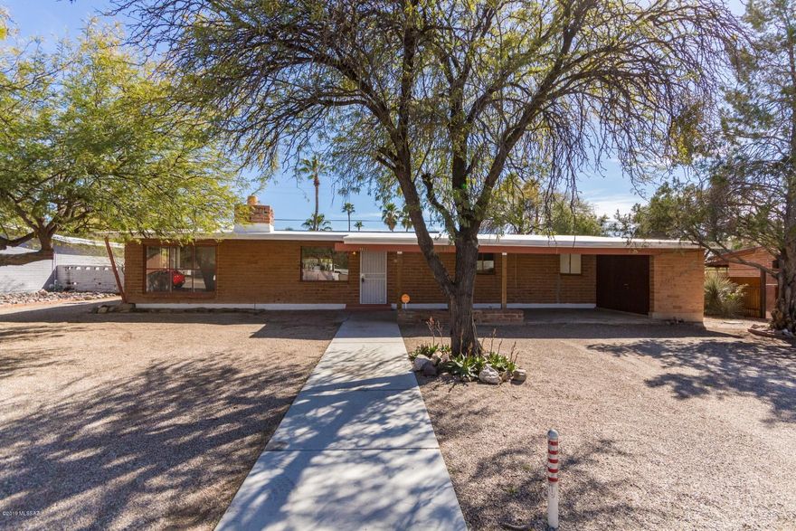 Charming 4 bedroom brick home nestled in the Casas De Carlos neighborhood! This home welcomes you to a bright and open great room with beautiful tile flooring, painted exposed brick, two-way fireplace, and exposed beams.  The galley style kitchen has double sinks, and ample counter space. The bedrooms are very spacious with updated vanities. The spacious backyard is primed and ready for your personal touches. This home is within minutes Tucson Medical Center, Tucson Country Club, shopping and dinning. Don't miss out on this home, schedule your showing today!