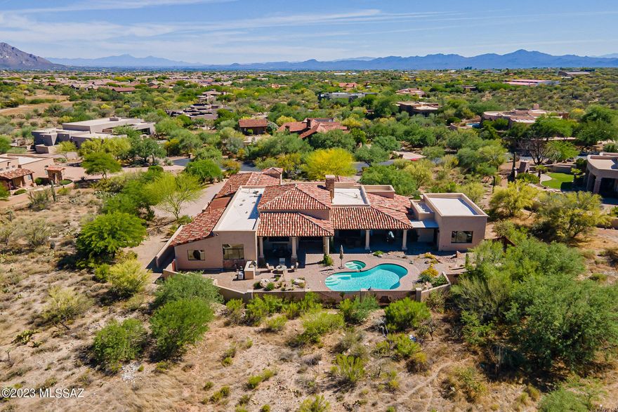 Privacy, serenity, seclusion, quality and timeless design on a cul-de-sac in guard-gated prestigious Stone Canyon, a welcoming community featuring Arizona's' top-rated golf course, fabulous activities and an excellent Club dining experience offering curated menus and wine tasting evenings for many occasions. This desert home is perfect for enjoying the casual yet sophisticated lifestyle found in Stone Canyon.  Be enchanted as you enter this Tuscan-contemporary masterpiece through a luxuriously landscaped courtyard and the handsome custom iron and glass double doors. Well-balanced luxurious finishes enhance the easy flow of interior and exterior spaces, with attention to detail as shown in the extensive list of Distinctive Features. Tumbled travertine and pecan wood flooring, a chef's kitchen providing two large pantries and the finest of appliances, a casita/ exercise room, salt-water pool with built-in cleaning, these are just the beginning of the list!
The great room provides plenty of space to relax, with soaring ceilings and a stunning linear fireplace surrounded in floor-to-ceiling black granite that handsomely contrasts with the alderwood cabinetry and rich travertine flooring. A cozy dining alcove with coffered ceiling is adjacent, overlooking the pool. The heart of the home is the glorious Chef's kitchen, with custom richly hued cabinetry, Taj Mahal quartzite countertops, top-end appliances including a Sub-Zero refrigerator, French café door oven, warming drawer, 48" Wolf cooktop with two additional ovens and TWO huge walk-in well-designed pantries...plenty of space for the seldom used turkey roaster, stock pot, slow cooker and Instapot! A custom-tailored island offers an array of counter space and generous sitting area, acting as a focal point in this fabulous kitchen. The delightful shaded breakfast patio is just outside the kitchen. An elegant walk-in wet bar includes a sub-Zero wine refrigerator and ice maker. The nearby powder room focuses on an elegant vessel sink and custom faucet.
The owner's suite is sumptuously appointed, with doors leading to the covered terrace and pool. A spacious bath area showcases a steam shower, Jacuzzi tub and an oversized walk-in closet with fabulous California Closets-style built-ins. Adjacent is the spacious casita, a perfect space for an exercise area, or easily closed off for a private casita with built-in under-counter refrigerator, access to the rear terrace, and with a private entrance through a lovely small courtyard. Two additional bedrooms are ample, with en-suite baths and well-fitted closets. The office looks out to Tortolita Mountain views, with doors leading to the shaded terrace & pool. 
The outdoor oasis features wrap-around covered terrace space accommodating multiple dining and gathering spaces, delightful for entertaining or just relaxing by (or in!) the pool and spa and enjoying views of the Tortolita Mountains and Arizona's famed sunsets. A built-in stainless barbecue is nearby. The oversized 3-car garage has epoxy finished floors, room for extra refrigerator, storage room and handsome metal doors. A huge beautifully finished laundry room, with stunning granite counters, built-in ironing board, more handsome cabinetry and large stainless sink, is nearby. Enjoy the resort lifestyle in Stone Canyon, conveniently located near all desired amenities in beautiful Oro Valley!