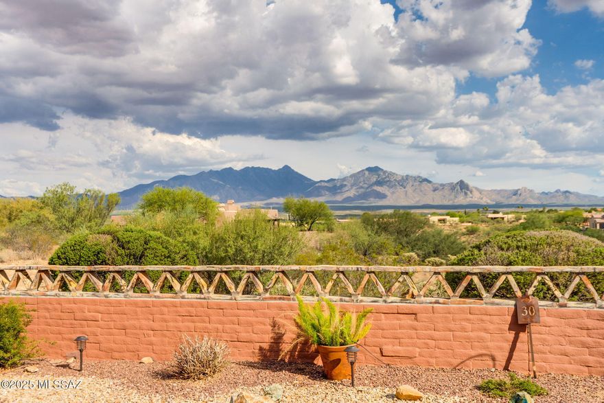 Discover the magnificent panoramic vistas of Santa Rita Mountain from this stunning and impeccably maintained residence in the prestigious gated community of Alamos. Range priced: Seller will accept or counter offers between $835,000 and $875,000. Combining sophisticated design, energy efficiency through a fully owned solar system, and stunning natural surroundings, this home offers a truly unparalleled lifestyle. The expansive great room boasts soaring ceilings, a gas fireplace, and large windows that perfectly capture the breathtaking mountain scenery. The contemporary floor plan effortlessly flows into the kitchen, adorned with exquisite cabinetry, granite countertops with a tile backsplash, a coveted gas cooktop, convection oven, stainless appliances, wine fridge, and a large breakfast bar illuminated by beautiful, rippled glass pendant lights which echo the breakfast nook's light fixture. The formal dining area is the perfect setting for hosting family and friends. The versatile den, with a beamed ceiling, provides a fantastic space adaptable to your needs - be it an office, lounge, or hobby room. The main suite is your tranquil hideaway featuring plantation shutters adorning the sliding door, through which you can also admire the spectacular views, and a spacious walk-in closet. The extensive ensuite bathroom presents granite counters, a high-end tiled shower, and a soothing garden tub to invigorate you. The split floor plan ensures the privacy you desire and provides access to two additional bedrooms and a guest bathroom outfitted with granite counters and a shower/tub combination. Convenient powder room perfect for guests. Enjoy the amazing mountain views, sunrises, and sunsets from the professionally landscaped backyard, complete with a porch featuring rolling screens and pavers. The laundry room comes equipped with a washer, dryer, and a handy sink. The extended three-car garage offers ample storage space with cabinets. Make the most of the amenities offered by the Green Valley recreation membership, including pools, gyms, pickleball courts, classes, shows, and entertainment. This residence is undeniably one of the finest homes Green Valley has to offer. Non-age restricted.