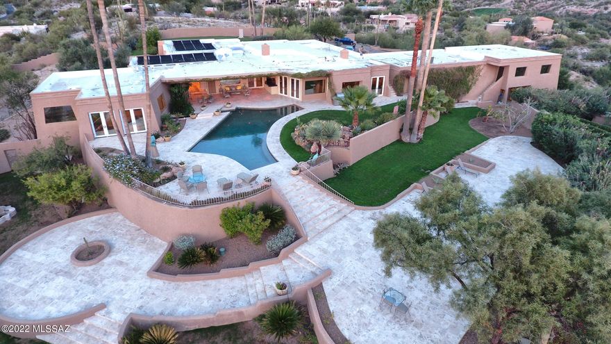 One's home has always been thought of as a place of refuge, and this is exemplified by Casa De Maya, a very private gated quintessential Tucson Foothills estate home on over 4 acres with dramatic view portals and expansive gardens. Envisioned for both large-scale entertaining and intimate family life, this is a luxurious compound providing a gorgeous primary home of 4 bedrooms and nearly 7000 sq ft, and outbuildings providing an additional 3300+ sf allocated to guest quarters, offices, maids quarters and a gym. Interior spaces range from open and soaring to cozy and intimate, blurring the boundaries between interior and exterior spaces. The gated and walled impressive entry gate opens to a long private drive to the primary home. Upon entry, you are greeted by the impressive entry and central hall establishing the main connection point of the primary home, with elegant Travertine flooring that floats seamlessly throughout the space. The heart of the home is the elegantly recreated Chef's kitchen with gorgeous finishes throughout, including contemporary custom cabinetry complimented with granite counters and sleek nickel-finished door pulls, with high-end appliances including a wine refrigerator. An adjacent pantry, also with granite counters, provides substantial additional storage and work space. The connected breakfast room provides an interactive space as it looks out to magnificent views of the pool and rear gardens. A sophisticated formal living room is graced with a welcoming fireplace and room for a grand piano. A nearby powder room evokes a style found in the glorious older homes of Beverly Hills. Across the unifying central hall is a formal dining room accommodating a stunning large glass table that can stay with the home. This hall leads to a charming smaller library with another delightful fireplace, and out to the stunningly beautiful pool, grounds with multiple patios and terraces, and an exquisite outdoor bar. Large wall space accommodating substantial artwork is found throughout the spaces, creating a lush living environment. Quiet sitting areas are found around the property, with covered and open patios unwinding to provide multiple spots for entertaining and enjoyment of the outdoors and views. The owners suite is concealed in the West Wing of the property, boasting a spacious bedroom/sitting area with glass shelving perfect for an art collection or family photos and opening onto the rear terrace and pool. The sumptuously appointed bathroom includes a mirrored dressing area with generous closed closets, and continues into a private sitting area with a spa, access to the outdoor pool through a swim-out feature and a luxurious glass-walled steam room. Three other bedrooms, two with fabulous en-suite baths, and an office space, complete the primary home. This truly is a "Grand Dame" of the Tucson Foothills. The three-car garage is oversized and provides several separate storage areas.  An adjacent one Acre lot is also available, please enquire.
About the area: The Catalina Foothills is located north of the city downtown area, with easy access to cultural events, the U of AZ and outstanding medical facilties. This area is known for the beauty of the Sonoran Desert, incredible views, fine dining and shopping, excellent schools, world-class golf and tennis resorts and several country clubs.