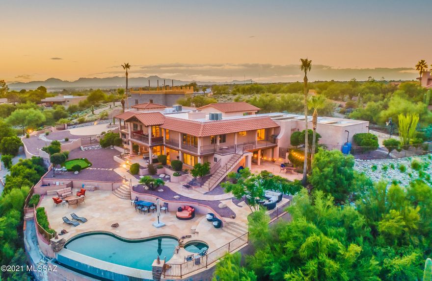 RANGE PRICED: SELLER TO COUNTER OR ACCEPT OFFERS BETWEEN $1,400,000-$1,500,00. Private gated entrance leads to magnificent property on elevated lot at the end of cul-de-sac in highly desirable Catalina Foothills. FIVE BEDROOMS: One Owner's EnSuite on Main Level, Two Jr EnSuite Bedrooms plus Two Additional Bedrooms on Lower Level. FIVE BATHROOMS! TWO OFFICES! Custom Features Throughout! Gourmet Kitchen: SS appliances, Wolf gas stovetop, SubZero refrigerator, breakfast nook, walk-in pantry. Dining Room shares dual sided fireplace with Formal Living. Spacious Owner's EnSuite (main level): Bonus room, private patio, dual vanities, shower, jacuzzi tub, and separate bidet. Breathtaking winding (lighted) staircase leads to lower level to Family Room. Wraparound covered balconies/patios...CONT >>> Private gated entrance leads to palatial property perched on elevated lot at the end of cul-de-sac in highly desirable Catalina Foothills. VIEWS FROM ALMOST EVERY ROOM! Custom Features Throughout! Gourmet kitchen: SS appliances, Wolf gas stovetop, SubZero refrigerator, breakfast nook, walk-in pantry. Dining Room shares dual sided fireplace with Formal Living. Spacious Owner's EnSuite (main level): Bonus room, private patio, dual vanities, shower, jacuzzi tub, and separate bidet. Classic movie worthy circular lighted staircase leads to lower level to Family Room. Two of four lower level bedrooms are en suite. Wraparound covered balconies/patios with breathtaking mountain, sunrise and city night light views. Negative edge pool, spa, putting green, 4-car garage, circular drive, owed solar!!

Upon arrival, you are greeted by the double door entry under a gable roof. The stately grand foyer leads to seamless indoor/outdoor living and entertainment spaces. Exquisite travertine flooring in all rooms except Formal Living Room where real wood flooring glamorizes the experience. Vaulted wood beam ceilings enhance the warmth, comfort and character of this Spanish inspired home. Thoughtful floorpan reflects the Primary Owner's Suite on the main level, with TWO ADDITIONAL generously sized En Suite bedrooms on the lower level. Two Offices/Dens: One on the main level and one on the lower level. Two wet bars: One on the main level, and one on the lower level. Outside you'll find a dragonfly inspired flagstone garden area, rain harvesting system, composting, as well as extended concrete aggregate circle drive allows for additional parking and leads to the four car garage.