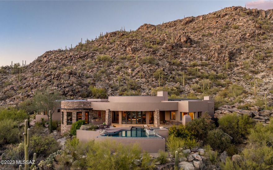 Luxury living awaits you w/mesmerizing city light and endless mountain views.  Nestled in the hillside rock outcroppings of guard gated Canyon Pass at Dove Mountain, this Ron Robinette designed home is drenched with magnficent views from basically every room in the home. Ron's renowned recessed ceilings w/accent lighting is a plethora of rooms - what a spectacular and relaxing setting in the evenings, dusk & dawn. Quality block construction.masonry walls - soft curves graciously invite from room to room. Beautiful stoned wall interior/exterior entry. Many rooms w/quiet power shades.  Highly desired south facing backyard viewing of city lights. Endless is the true word to describe the abundant storage in this home - even the garage -most all w/air conditioning. A truly quality custom home.