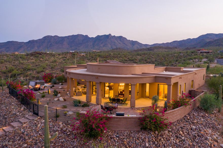 Exceptional Contemporary Southwestern style home built in 2017 featuring a flowing floor plan with 3 bedrooms with ensuite baths, guest ½ bath, 2 offices, and 4 car garage, on a saguaro studded 3.3 acre homesite. Enter through the custom double entry door into the open great room with gorgeous stack stone gas fireplace, 14' ceilings, skylights, large floor-to-ceiling view windows, and 2 sliding glass doors that embrace the endless spectacular mountain views. Chef's Kitchen features Alder hickory kitchen cabinets, Pegasus granite countertops, under counter and cabinet lighting, stainless steel appliances, breakfast bar, and dining area with pendant lights. Luxurious master suite is complete with oversized walk-in closet, private entry to back patio & large picture window showcasing views of desert saguaros, city lights, and the Catalina mountains in the distance. Ensuite bathroom features a spacious walk-in shower with separate soaking tub and dual granite vanity. Outdoor living at its finest begins with 4 patio areas equipped with ceiling fans, TV hook up, wired for security cameras, 3 pump 61 jet Cal spa, outdoor shower and relaxing sitting areas with breathtaking views in all directions. The outdoor kitchen is equipped with Napoleon grill and side burner. Lush landscape with walking paths and trails throughout the property. 
Additional special features of this home include 8' Alder doors throughout, extra foam insulation in walls and roof, fully-plumbed central vacuum system and water softener loop, hot water circulating system, wired surround sound speakers and bio-microbic septic system. Exterior was painted and the roof was resealed in summer 2020. Entire home is surge-protected at service panel. Property is on city water, but private well is present and needs a pump and finishing touches. Located in a gated community with NO HOA. RV space is available with a gravel parking loop in the back with a  stained concrete driveway in the front leading up to the extra large 4 car garage with 18'x8' insulated doors. You will find yourself anticipating the trip home, remembering the relaxing solitude of this custom designed home overlooking the Tucson city skyline.