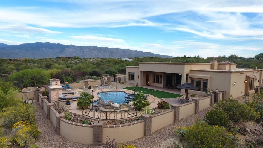 The builder of this 5 bedroom, 4.5 bathroom 3,703 sq ft custom home capitalized on the stunning panoramic mountain views.   The living room has unobstructed north facing full length windows with views of resort-like backyard with Catalina Mountain backdrop.   Enjoy outdoor living with a huge covered patio, hot tub, pool, fireplace, artificial grass, sandy beach area, tiki torches plumbed to home's propane tank, fountains, a putting green and views in every direction. Private gated driveway leads you to welcoming courtyard with fountain and great views through the house to the stunning backyard.  Kitchen is a chef's dream with all new Wolf, Sub-Zero & Kitchen Aid appliances in 2016. Don't miss the Virtual Tour on this listing. In the photos tab click Virtual Tour (U), then 3D Tour. High ceilings are accented by 8-ft alder doors and Andersen windows throughout.  400-Amp service panel, 3-car garage with epoxy floors and built-in vacuum.  Dolphin Premier Robotic In-Ground Pool Cleaner stored in garage and Solar Breeze Pool Skimmer do not convey.