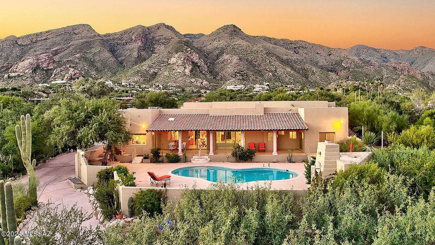 Situated on 1.1 private acres within the prestigious, guard-gated Skyline Country Club Estates, this exquisitely remodeled Southwestern contemporary home offers 4,835 sq. ft. of living space with breathtaking panoramic views of the mountains and city skyline. Completely reimagined between 2016 and 2017, this four-bedroom, four-and-a-half-bath residence (including three en-suite baths) blends timeless elegance with modern sophistication.
Step into the expansive living room where soaring ceilings and designer ceramic tile flooring create an inviting sense of grandeur. The formal dining room, with its dramatic vaulted ceiling, comfortably accommodates 12 or more guests—perfect for entertaining on any scale.
The spacious family room, open to the gourmet kitchen, features a cozy fireplace and a large Pella retractable sliding door that seamlessly connects the indoors with the stunning outdoor living areas. Designed for the discerning chef, the kitchen boasts sleek quartz countertops, high-end self-closing cabinetry, and a convenient butler's pantry.
Retreat to the serene primary suite offering tranquil mountain views, a custom walk-in closet with built-ins, bamboo flooring, and a luxurious bath complete with a bidet. Three of the four bedrooms feature bamboo flooring, while the bathrooms are appointed with travertine tile showers and flooringcomplemented by marble tile in the fourth bath.
Additional highlights include a single-level floor plan with no interior steps, two AC units plus a mini-split in the guest bedroom, and an oversized three-car garage.
Step outside to enjoy a beautifully designed backyard oasis featuring an expansive covered patio, a sparkling pool, a striking outdoor fireplace, and a spiral staircase leading to a rooftop deck with spectacular 360-degree views. The meticulously landscaped grounds offer walking paths lined with mature trees, lush desert foliage, and majestic saguaros.
As part of the Skyline Country Club community, residents also enjoy access to top-tier amenities including golf, lighted tennis and pickleball courts, a pool, spa, and a state-of-the-art fitness center.