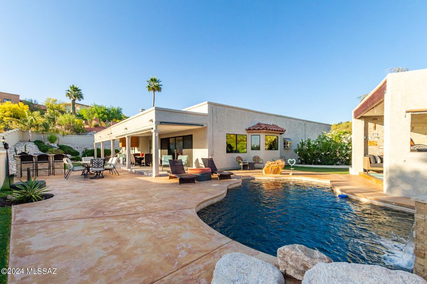 This fully-fenced residence boasts private streets, a 2-car garage, low-maintenance yard and desert landscape, Once inside discover a great room w/high ceilings, recessed lighting, a soothing palette, durable etched concrete flooring, & an inviting fireplace for cozy evenings. The kitchen boast a dry bar, granite counters, white shaker cabinets w/crown moulding, pendant lighting, a tile backsplash, SS appliances, a pantry, & an island w/breakfast bar. The main bedroom offers backyard access & an ensuite with dual sinks, a soaking tub & steam shower, skylights, and a walk-in closet. The enchanting backyard showcases a sparkling pool, covered patio, multiple fire pits, a serene water feature, a built-in BBQ, a Cabana with a dry bar, and stunning city views. Luxury Indoor/Outdoor living