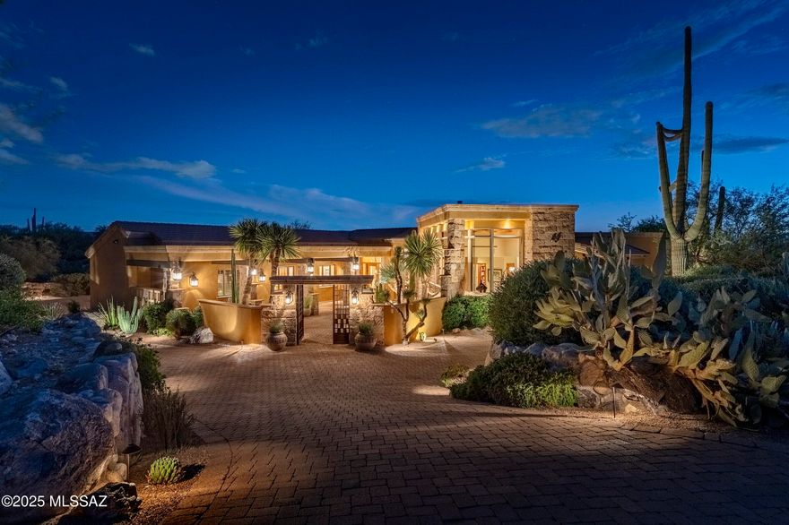 Located behind the private secondary gates of Pima Gardens in Pima Canyon, this architecturally refined desert estate offers privacy, scale, and exceptional design. The property spans 6,631 Sq Ft, including a 5,667 Sq Ft main residence and a 939 Sq Ft detached guest house. A gated courtyard entry with Cantera stone water feature leads to a dramatic foyer with travertine floors, birch-paneled ceilings, and knotty alder beams. The home is thoughtfully laid out to maximize natural light and capture views of the Catalina Mountains and surrounding desert landscape. The formal living room features expansive glass walls, creating a seamless indoor outdoor connection. A climate controlled wine gallery with approximately 900 bottle capacity and an adjacent dining area open directly to outdoor terraces, ideal for entertaining. At the center of the residence, the chef's kitchen features dual islands, imported custom cabinetry, granite countertops, and professional grade appliances, opening to an inviting informal living space with a Cantera stone fireplace. A breakfast nook connects to its own private patio overlooking rock outcroppings, and saguaro-studded terrain. Additional highlights include a dedicated theater designed for an elevated cinematic experience. The primary suite is privately positioned within the west wing and offers a true retreat, featuring custom alder and birch ceiling details, a two way fireplace, a sitting room, and direct access to a private terrace with sweeping desert views. Additional en-suite bedrooms continue the home's consistent level of craftsmanship and finish. The detached guest house provides full independence with its own kitchen, living area, fireplace, and private terrace, ideal for extended guests or multi-generational living.

Outdoor living is exceptional, with expansive Cantera verandas, an outdoor chef's kitchen, multiple courtyards, and 20 foot sliding glass walls that fully retract to create true indoor outdoor flow. The negative edge pool and spa integrate into a one of a kind Cantera water feature with handmade stone spheres and cascading water elements. A lower level turf area adds functional green space for play or gatherings, surrounded by mature desert landscaping and specimen plantings.