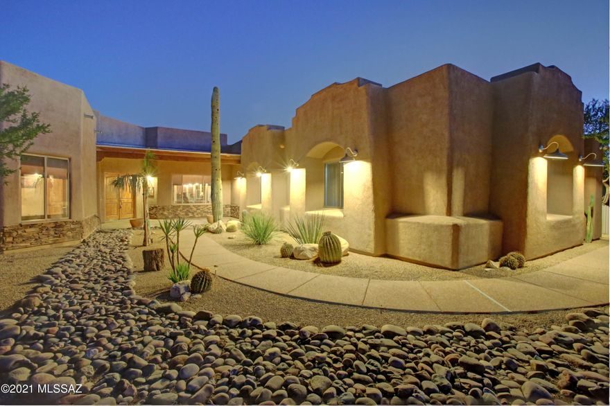Exquisite Southwestern style ranch with detached guest home nestled on 6.86 acres yet conveniently located to the Oro Valley CC. This home features scored concrete floors, 8' alder doors, distinctive wood carved columns. Gourmet kitchen w/rough edge granite counters, double ovens & alder cabinets. Formal dining offers custom wall cabinet w/sink & wine refrigerator. From the spacious Master closets. Two ensuite bedrooms. Executive office includes custom cabinetry. Welcome your guests to their own private abode boasting a living room, kitchen & bedroom. Breathtaking panoramic Pusch Ridge views from 2000 sqft wrap-around rear patio w/outdoor cook station overlooking oasis style pool/spa.