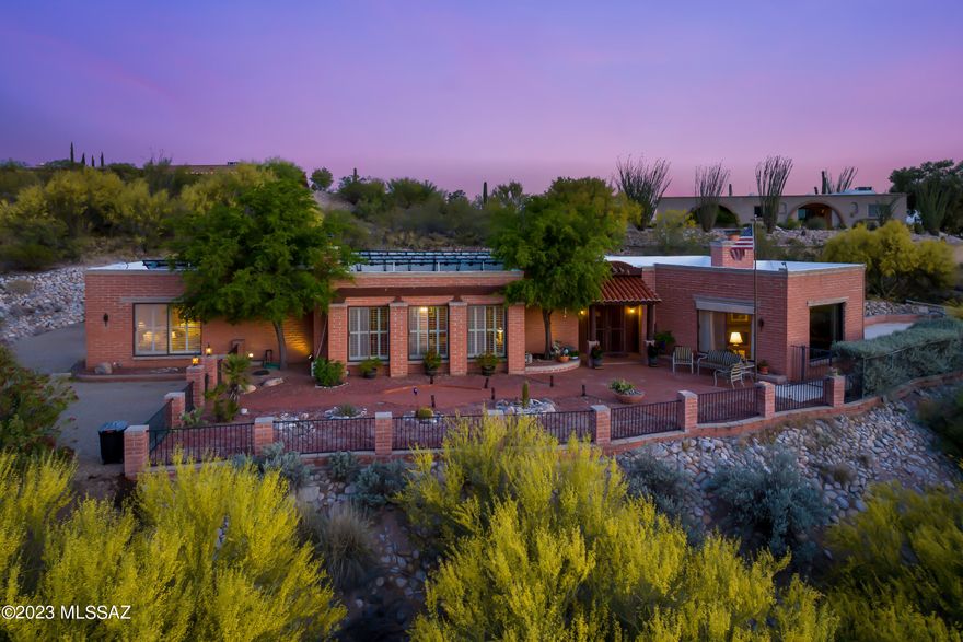 Fabulous Territorial home situated on an elevated hillside lot with unobstructed Catalina Mountain views. Enter through the large courtyard to this unique home featuring a spacious living room with large picture windows and a 3-sided brick fireplace. Expansive separate dining area boast a wood burning fireplace, a wall of windows and is ideal for entertaining or making memories with friends or family. The spacious updated kitchen offers granite counters, prep sink, a breakfast bar, that opens to a large family room.. Additional features include diamond shaped Saltillo floors, skylights, fully OWNED SOLAR, and an expansive garage and plenty of storage. Private backyard is ideal to relax by the pool or under the covered patio and watch the colorful Arizona sunsets the Catalina Mountains. Skylights throughout main areas bring in tons of light. Take your favorite cocktail and relax by the saltwater pool or under the oversized covered patio and watch the colorful Arizona sunsets. All this plus OWNER OWNED SOLAR, 2 car garage, storage room and plenty of parking.