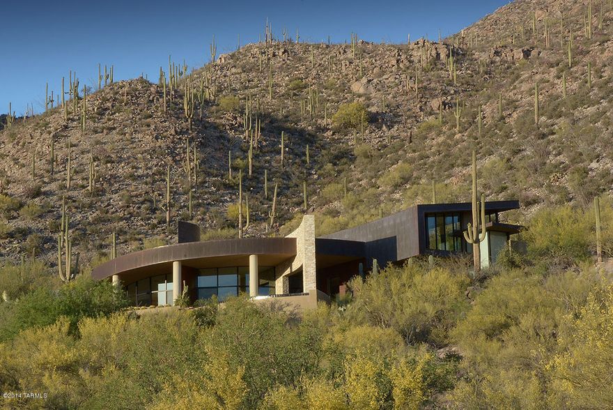 Range Price- Will accept offers between $1,699,999 and $1,799,999. As featured in Luxe and Tucson Lifestyle Magazines, this design-award winning home hugs dramatic rock formations, set on a spectacular hilltop lot with breathtaking panoramic vista views;  exterior is clad in ledgestone and patina copper, blending organically with nature's gorgeous surroundings.  Interior design by Lori Carroll is perfection, Windows everywhere strike the perfect balance between tall interior spaces and lifestyle intimacy; fabulous floorplan makes for casual livability, with a bonus den/office for a multitude of uses.  Everything the eye can see is stunning and practical at the same time.  Browse the photos to see for yourself and don't miss the gasp-worthy negative edge pool and jaw-dropping views