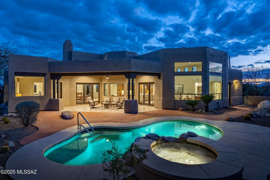 Nestled within the prestigious, cobblestone-lined streets of The Enclave at Pima Canyon in the exclusive guard-gated community of Sin Vacas, this privately situated residence offers an unparalleled connection to the vast and rugged beauty of the Catalina Mountains. Thoughtfully crafted with a refined sense of design, proportion, and materiality, this timeless property embodies classic detailing with modern elegance. The flexible floor plan, featuring four bedrooms and four bathrooms, seamlessly balances form and function, creating an inviting living environment where every detail has been carefully considered. At the core of the residence, the chef's kitchen is a study in material contrast and precision craftsmanship. Custom millwork defines the space, where knotty alder natural wood cabinets meet a striking sage green center island. Expanses of white quartz surfaces establish a serene, monolithic quality, reinforcing a sense of clarity and restraint. Flowing seamlessly into the adjoining dining and formal living areas, the kitchen fosters an atmosphere that encourages both gathering and quiet reflection. From the great room, large glazed openings frame the surrounding landscape, allowing natural light to animate the interiors throughout the day. Multiple points of egress dissolve the threshold between indoors and out, cultivating a continuous spatial dialogue between the architecture and the rugged desert terrain beyond.

The primary suite is privately positioned on the Northeast end of the residence, featuring large dual walk-in dressing closets and a spa-like bathroom. The bathroom includes a walk-in shower with body sprays and a separate soaking tub. Adjacent to the suite, the den/office offers south-facing city views and overlooks the cozy front courtyard. Thoughtfully designed with a split bedroom floor plan, the residence includes two additional ensuite bedrooms, as well as a fourth bedroom which could be utilized as a flex space, with its bathroom also serving as the pool bath.

Adding to the home's energy efficiency and sustainability, a Tesla solar system provides an alternative power source to reduce energy costs. The 13.78 kW DC photovoltaic system consists of PV modules, an inverter, and a mounting system designed for long-term operation. This system is designed to increase energy efficiency harnessing Arizona's natural resources and supporting sustainable living.

Encircling the home, a series of thoughtfully positioned outdoor living spaces create an effortless flow between shelter and landscape. Here, one is fully immersed in the tranquility of the natural surroundings. The sun-drenched terrace, designed for seamless indoor-outdoor living, offers al fresco dining with breathtaking views of the Catalina Mountains. Overlooking a resort-like pool, this space serves as an extension of the home, a place where lifestyle and nature exist in perfect harmony.