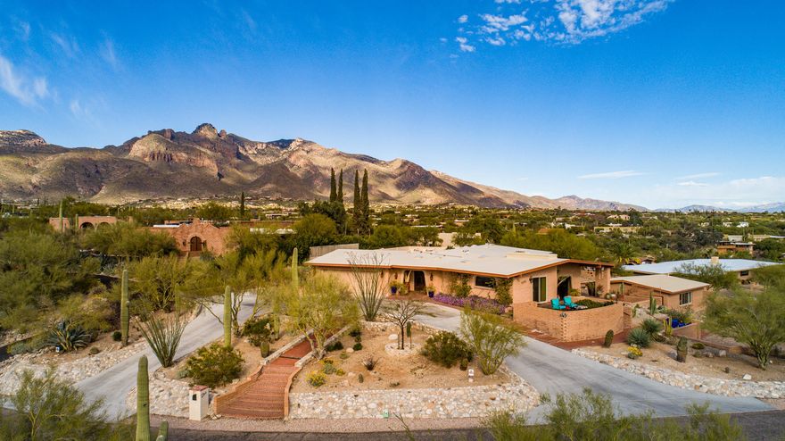 Unique updated custom built southwestern contemporary 5 bed/4 full bath, split floor plan 3,954 SqFt home on elevated premium .62 acre lot, providing spectacular city views in desirable Santa Catalina Estates in North Tucson. Enjoy the best of both worlds, the vintage character and charm of a 1974 territorial with updated modern amenities, attached 615 SqFt finished 2 car garage, endless exercise pool w/current generator and underwater treadmill complete w/retractable cover, covered front and back patios, pizza oven and complete outdoor kitchen! Enjoy multigeneration living split floor plan and separate 747 SqFt permitted one bed/one bath w/kitchenette guest house. Featuring: concrete circular driveway, brick walkways, flagstone patios, custom stonework, decorative pony walls, rainwater drainage, tree wells, raised flower garden, manicured front and back landscaping including irrigation, mature vegetation with native desert plants, cactus, flower, vegetable gardens, mesquite and fruit trees (fig, lime, pomegranate, & grapefruit), artificial grass, outdoor security cameras and landscape lighting.  Inside buyers will appreciate 18" diagonal porcelain tile throughout, comprehensive cable, data and telephone wiring, Accura security system w/alarm, smoke & heat detectors and full 360-degree perimeter CCTV with 14 security cameras and digital video recorder,  textured ceilings (no popcorn), exposed wood beams, 10 skylights, designer paint, energy efficient double pane windows w/window screens throughout, exposed brick walls, recessed lighting, green LED lighting fixtures, Sonos zone players & Sonance speakers throughout interior/exterior, intercom system (including between main and guest house), Enviro whole house water filter and water softener. Alder wood internal doors, wood trim and cabinetry throughout, California Closets cabinetry and shelving in master bedroom, den closets, built-in shelving in family room, coffee bar, pantry/laundry room, linen closets, and garage, updated brushed nickel fixtures and hardware, updated modern lighting fixtures, modern ceiling fans, spacious master bedroom suite with massive custom window for shimmering city views, wood burning fireplace, separate master den, walk in closet, updated master full bath with executive height marble dual sink vanity, tiled walk in shower. At the heart of the home, open concept kitchen with adjacent formal dining room, gorgeous full slab granite counter tops, bar seating, exposed brick surrounding 5 burner gas stove, stainless steel exhaust hood, and dual GE Profile convection ovens, skylight, coffee bar adjacent to walk in pantry/internal laundry room. Outside buyers will delight with outdoor covered living area with permitted kitchen (536 sq ft). Top-of-the-line Twin Eagles appliances, including 42" gas grill with infrared rotisserie, sear, warming drawer, double burner and griddle, two-drawer refrigerator, ice maker, sink with cover, trash drawer, and plentiful storage cabinets and drawers, all of stainless steel. Also Vent-A-Hood island hood, Infratech ceiling heaters, ceiling fans, misting system, pull-down sunshades, ceiling speakers, television, full slab granite countertops, and more = enjoy outdoor dining and entertainment all year long! Woodburning oven (pizza and more!) adjacent from the stunning outdoor kitchen.   Updated permitted 400 amp electrical panel, electrical and plumbing repairs and upgrades, including 220 volt service line, new natural gas main line and new sewer pipe lining.  Come view this stunning property while it is still available, it will not last long!