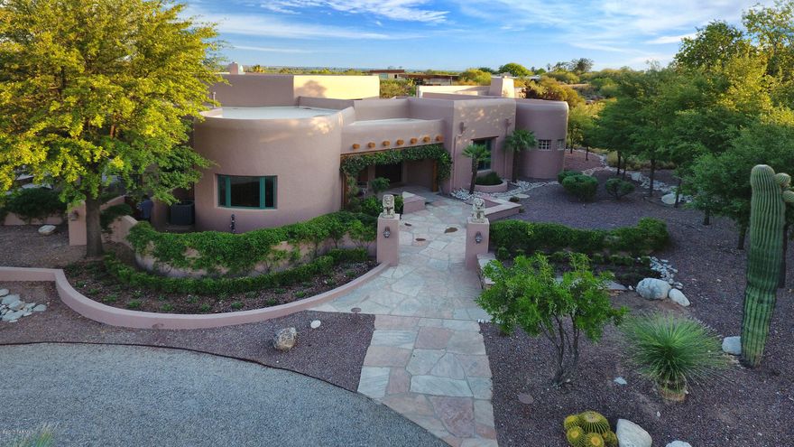 Welcome to an opportunity to reside in the renowned Tucson Canyon Ranch Wellness Resort in an unparalleled Southwestern Santa Fe style residence with fabulous upscale amenities in both the home and the community. The home provides the finest of construction and design details, and has recently been renovated and restored both inside and out at significant expense to be one of the most outstanding homes available in the area. Designed by highly respected and well known Tucson architect, Ron Robinette, in the Pueblo Revival style with a contemporary flair, the home’s thick walls, rounded features and extensive hand-hewn vigas, corbels, and latillos are balanced by soaring ceilings and a softly contemporary aesthetic expressed in exquisite materials, fabulous kitchen and bathroom elements, and glorious views from everywhere through an abundant utilization of tall windows and doors. 
The home incorporates many unique curved elements that provide a warmth to the spaces, as if the home were embracing you. The elegantly gracious entry foyer is topped with a handsome viga and latillo ceiling and opens to the living, kitchen, dining, bedroom and the office.  Handsome hand-carved lintels and corbels frame the entries to each area. The dramatic kitchen welcomes with a long oval island topped with gorgeous gleaming Italian Verde Grigio thick marble and an extensive matching curved wall of Verde Grigio marble counters and storage. Featuring the best of appliances, with a 6 burner + griddle Viking stove, Dacor wall ovens, Sub-Zero refrigerator, warming drawer, wine refrigerator, two sinks, pullout baskets and a large pantry, gourmet chefs or caterers would be quite comfortable here. A comfortable desk area includes a lighted curio cabinet that can display mineral or other collectables. The rounded northeasterly end of the kitchen provides a stunning direct view of the distinctive summit of Thimble Peak amidst the Santa Catalina Mountains, promising eye-opening sunrise views over morning coffee. The pentagonal dining room promises convivial intimate evenings under the beautifully double-coffered gracefully lit ceiling with a view to the outdoor terrace and warming kiva fireplace beyond. The salon, a warm gracious space for gathering and relaxing, is defined by its soaring ceilings and accented by a contemporary version of a traditional beehive fireplace, this one reaching to the 20 ft tall viga and latillo ceiling. Dramatically high clerestory windows abound for plenty of natural light. Glass doors lead outdoors to a long and deep traditional covered patio area with more richly carved and distressed corbels and lintels supporting the overhang, lovely irrigated gardens and mountain views in the distances. The curvature continues outdoors, with gracefully rounded outlines for the two levels of terraces and surrounding walls enclosing the home. A rustic stone waterfall enhances the sense of nature found in the warm materials utilized throughout.  Back inside, the powder room features Sherle Wagner gold-plated fixtures and accessories with a lovely sink set in an antique dresser topped in marble. The generously sized office looks out to more mountain views beyond the property's gardens, and has a handsome built-in bookcase hand-built by a local craftsman. Two ample guest bedrooms each have en suite baths and desert or garden views. The spacious master bedroom suite provides an oval wall of windows also overlooking desert views, and a gas fireplace set in a beautiful surround with a marble hearth. Look upward to the ceiling in this magnificent space, softly curved between whitewashed thick viga beams, a very unique and handsome feature. The real treat is the master bath, with exquisite Azul Blue Macauba Quartzite counters from Italy, creamy travertine marble floors, Jacuzzi tub surround and an oval travertine-lined shower. With more delightful views and a full make-up counter for the lady of the home, this is the spot for a glass of champagne while dressing for that special event, or relaxing in the Jacuzzi after a workout. And what a workout can be had, as Canyon Ranch has the most sophisticated array of exercise options imaginable, from the latest in equipment to the most amazing variety of classes guaranteed to help anyone accomplish their fitness and wellbeing goals. The Ranch and its affiliated Canyon Ranch Institute are famous world-wide for the creative and life-altering opportunities afforded to participants, from improving personal fitness and finding serenity, to recovering from traumatic injuries, to the development of healthy lifestyles. With over 400 fitness, educational and fun activities each week, plus the array of personal services available from a never-ending menu of massages, facials, purifying rituals, ayurvedic treatments and so much more, constantly updated, no one will ever tire of this cornucopia of choices. As a resident of the Ranch, these facilities are always available to you and your guests. Want a massage in the evening after dinner? No problem! Just slip  into your robe and walk over to the nearby Massage Center, afterwards take a dip in the beautiful private hot spa before slipping into sleep back at your own beautiful abode. These opportunities to own a home at the Ranch do not come often, and this home is one of those fabulous opportunities. We look forward to sharing it with you. A current appraisal for $3,000,000 is available upon request.