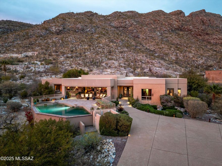 Perched majestically against the dramatic backdrop of Pontatoc Ridge in the exclusive Coronado Foothills Estates, this extraordinary 4,088 square foot residence transcends the ordinary concept of ''home'' to become something far more profound—a personal desert sanctuary where architectural brilliance meets untamed natural beauty.
Situated on 1.56 gated acres in the prestigious Catalina Foothills, this custom masterpiece represents the pinnacle of desert living, where each design element has been thoughtfully curated to honor both sophisticated comfort and the magnificent Sonoran landscape that surrounds it.
The residence is defined by its harmonious dialogue with the environment. Strategically placed oversized windows function as living canvases, transforming each room into a gallery where light, shadow, and panoramic vistas become integral design elements. Constructed with enduring solid block and adorned with custom Sonoran mesquite hardwood floors and elegant travertine, the home embraces both refinement and authenticity. The hallway, great room, and master bedroom suite feature exquisite Imperial Plaster walls, adding a subtle richness and texture that complements the architectural significance of the space.
The culinary sanctuary reflects global sophistication, featuring a professional-grade Thermador range, premium appliances, artisan cabinetry, and an island perfectly positioned for both serious cooking and social gatherings. As the heart of the home, this space is designed for creating memorable evenings against the backdrop of mountain views so captivating they rival fine art.
Retreat to the primary suitea sanctuary within the sanctuaryfeaturing dual luxury bathrooms, a supersized custom walk-in closet, and floor-to-ceiling windows that frame the ever-changing desert tableau. Two additional sophisticated bedrooms share an elegantly appointed bath, providing sumptuous accommodations for family or guests.
Step outside to discover a private resort-caliber environment where the heated infinity-edge pool and spa invite both refreshment and reflection. Multiple entertainment zones offer perfect settings for morning coffee amid visiting wildlife, afternoon dips in the shimmering pool, and evenings enjoying spectacular sunset views across the Tucson Valley.
What truly distinguishes this property is its extraordinary connection to the natural world. A custom water feature at the property's edge creates a serene oasis that attracts the region's remarkable wildlife. Desert bighorn sheep, native to the adjacent ridge, regularly visit this water sourceoffering residents the rare privilege of observing these majestic creatures from the comfort of home. The thoughtfully designed landscape includes additional water elements that blend seamlessly with native terrain, creating a harmonious transition between cultivated grounds and the wild beauty of the Sonoran Desert.
This rare offering includes thoughtful amenities that elevate everyday living: a private elevator connecting the main residence to the garage, two distinctive fireplaces, and exceptional privacy provided by both natural topography and secure gated entry.
More than a luxury residence, this property represents an invitation to extraordinary livingan opportunity to become the next steward of a home that celebrates the profound connection between sophisticated design and the untamed beauty of the Sonoran Desert. For those who recognize that true luxury lies in authenticity, privacy, and the daily celebration of natural beauty, 4361 E La Paloma Drive awaits.
Properties of this caliber and location rarely become availablea private viewing is strongly recommended, as this extraordinary desert sanctuary will not remain on the market for long