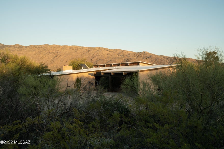 Nestled into the desert on over 3 acres sits the Javelina House, designed by Architect Robert Swaim. Completed in 1972, and is one of the Architects early commissions.  Well sited on an East / West axis, this home steps down with the contours of the property allowing for a true indoor & outdoor connection.  The original plan remains intact, with a separation of public and private spaces connected via the main entry hall. Natural light floods the interiors in all directions. Extended overhangs shelter sliding doors & windows  that open to patios, gardens and the desert horizon beyond.  A material palette of brick, concrete, glass and wood bring warmth and texture to the space. Interior wood casework and built-ins, brass hardware, and 3x6 aqua tile add to the patina of the home. The pool and spa were added after the home was completed, sited and structured with generous steps that also reflect the rolling topography of the desert landscape. A carport for 2 vehicles, outdoor enclosed storage and fenced area for gardens and chickens are also found on the property.  Located in close proximity to the spectacular Saguaro National Park East, this modern gem is ready for its second owner.