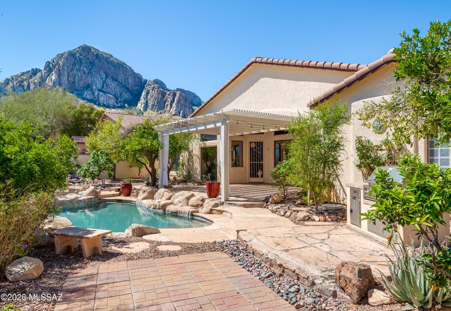 Located in prestigious guard-gated La Reserve at Bighorn Point, this beautifully maintained 2,497SF, 4BR/2.5BA home backs to open space with stunning Catalina Mountain and city light views. Spacious floor plan features formal living room with fireplace, formal dining room with coffered ceiling, soaring vaulted ceilings, plantation shutters, and family room open to kitchen. Beautiful kitchen offers granite counters, tile backsplash, center island, breakfast bar, newer stainless appliances, pantry, and casual dining nook. Primary suite includes double-door entry, patio access, walk-in closet, and updated bath with soaking tub and tiled shower. Resort-style backyard features heated PebbleTec pool/spa with waterfall, covered flagstone patio, extended ramada, built-in BBQ, pizza oven, mature fruit trees and exceptional privacy. Owned solar, new HVAC 2020, new roof 2021, new water heater 2025, EV charger, and more. Exceptional Oro Valley location near hiking, golf, shopping, dining, and Catalina State Park.