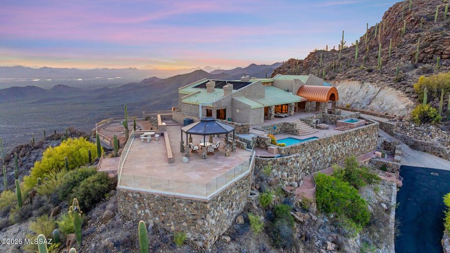 Tucson's Crown Jewel! A rare opportunity to own the highest home in the Tucson area with astonishing 270° vistas stretching 60 miles across the city and desert to the surrounding mountain ranges and beyond! Begin every morning with a brilliant sunrise emerging out of deep orange dawn glow. End every day with glorious sunsets over the Sonoran Desert, and behold the most dazzling sweep of city lights at night, with shining stars above. It's an unparalleled, constantly evolving, awe-inspiring display of color and luminosity you can experience from the comfort of your architect-designed, 4-bedroom, 5-bath home on 4 acres--smartly remodeled in 2024--with ultimate privacy, tranquility, and security behind three gates. This is the only home fully situated up on the crest of the Tucson Mountains, at almost 4000 ft elevation, a world away from urban bustle but only 20 minutes to downtown. The west side of the property borders the protected lands of Tucson Mountain Park, ensuring lasting peace and quiet with up-close views of rocky Tower Peak. The mountain ridge has its own pleasant micro-climate, 5-7° cooler than the city in summer with gentle warm desert evenings ideal for outdoor living and stargazing.

On approach, you pass through two successive gated entry points, then drive up the private road lined on both sides with beautifully crafted stone walls. Arriving at the estate, you'll be surprised, delighted, and uplifted by the expansive scenery, especially when a quick walk around the home reveals that the southern and western views are just as stunning as the eastern spectacle. The elegant split-face-block and stone house is surrounded by spacious flagstone and brick patios featuring wrap-around glass fencing for maximal sightlines. Enjoy the solar-heated pool and large built-in spa that can hold up to 10 people comfortably, as well as an open-air gazebo with mesmerizing vistas for shaded entertaining. The property features more than 100 saguaro cacti, visiting hummingbirds, soaring ravens, and the moon so big and close it feels like you can touch it.

The bright interior of the home features new LED recessed lighting throughout, all new appliances, and fresh flooring treatments (2024). You'll have a primary kitchen with additional kitchenette/wet bar, both of which open to a great room with wood-burning fireplace, cathedral ceilings, high clerestory windows, and a wall of glass framing stunning views of the Catalina Mountains and the city far below, which becomes a dazzling panorama of light at night. All 4 bedrooms have sliding-glass doors with patio or balcony access, creating a constant connection with the natural desert environment.

The primary bedroom features a stone fireplace and elegant en suite bath with an additional black-marble fireplace and spa tub with city and mountain views. A second extra-large bedroom at the opposite end of the house features its own city-view balcony with glass railing and a panoramic 9-ft-wide picture window looking west far across the desert.

The home has two independent HVAC systems (2023) for ample heating and cooling, augmented by mini-split HVAC units (2025) in the primary and west-facing bedrooms. The three-car garage has its own mini-split, toilet, utility sink, closet space, and refrigerator (2025). The gated entry features a new intercom system and security camera (2025).

Building a home in this magnificent location would be virtually impossible today, given current regulations and the significant cost of infrastructure, grading, and stonework. The benefits of many years of craftsmanship, engineering, and ingenuity are now yours to savor.

From this singular vantage point, many Tucson landmarks are in full view, including Mt. Lemmon (sometimes snow-capped in winter!), the Catalina Mountains, Saguaro National Park East, the University of Arizona, downtown Tucson, Golden Gate Mountain, and Saguaro National Park West, with Old Tucson and the Arizona-Sonora Desert Museum in the valley below. Farther west, you have a magnificent view of Kitt Peak and Baboquivari, the sacred birthplace of humanity in the Tohono O'odham tradition. This stellar property is so much more than a house--it's a precious opportunity to live at the scintillating intersection of desert, mountain, sun, and sky.