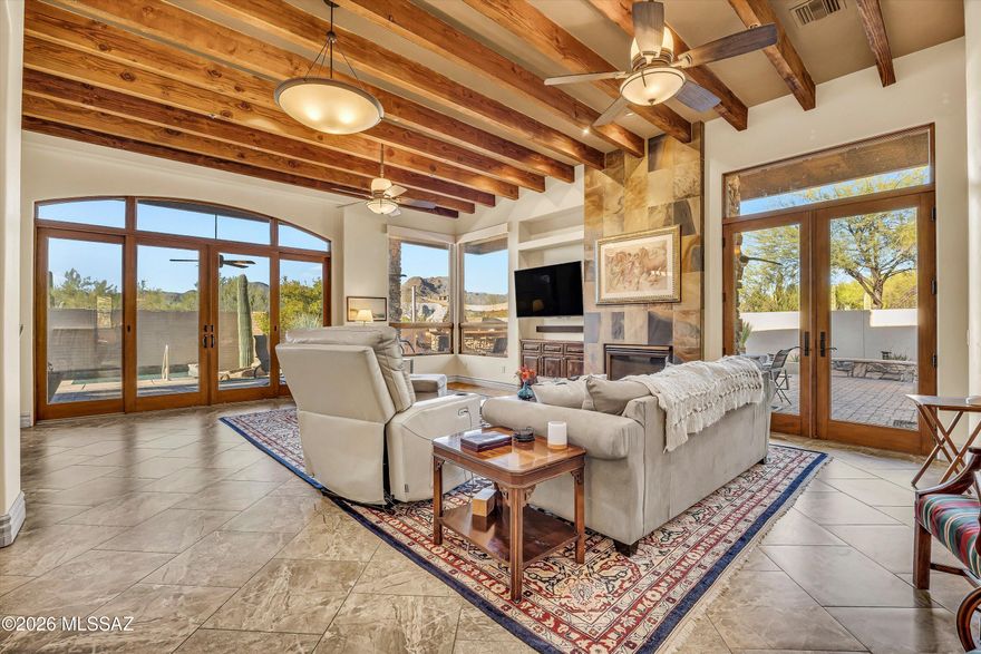 Wake up to sweeping Tortolita Mountain views, enjoy morning coffee in peaceful desert surroundings, unwind beside a rooftop fireplace under Arizona's sunset skies, and experience a home designed to fully embrace indoor-outdoor living. Set within the gated Sonoran Preserve--an enclave of just seven homes--this exceptional estate offers privacy, space, and architectural character on nearly an acre. A private front courtyard sets the tone for the home's architectural character, anchored by a striking stone fireplace and framed by warm paver hardscape and desert landscaping. Designed as an intimate outdoor living space, it offers a quiet place to gather, unwind, or enjoy Arizona's mild evenings before stepping inside.
The main residence features a thoughtfully designed split floor plan with soaring ceilings, exposed wood beams, and expansive windows that frame the surrounding desert landscape while filling the home with natural light. The great room is anchored by a dramatic floor-to-ceiling fireplace and opens seamlessly to the outdoor living spaces, where views and light take center stage.
The chef's kitchen is both functional and distinctive, featuring Viking Professional appliances with convection, a gas range with pot filler, dual dishwashers, sandstone countertops, and a striking mesquite island. Custom cabinetry and a hand-painted hood reflect the craftsmanship carried throughout the home. Adjacent dining spaces include a formal dining room with direct access to the courtyard--complete with a fireplace--creating a unique indoor-outdoor dining experience, along with a light-filled breakfast nook surrounded by windows.
The primary suite offers a private retreat with mountain views, direct outdoor access, and a spacious spa-like bath featuring dual vanities, a soaking tub positioned beneath a picture window, and a large walk-in closet. Designed for comfort and privacy, the home also includes a dedicated guest wing with a Jack-and-Jill bath, as well as a separate office or den with custom built-in cabinetry.
A detached casita provides exceptional flexibility for visitors or extended stays, complete with its own private entrance and well-appointed living space--creating a private retreat within the property.
Outdoor living is where this property truly excels. The backyard is thoughtfully designed for both relaxation and entertaining, featuring a saltwater pool with elegant water features, multiple covered patios, and a variety of distinct seating areas that create inviting spaces for both quiet moments and larger gatherings--all set against the backdrop of the surrounding desert.
The outdoor kitchen is equipped with a built-in BBQ, curved bar seating, and a wood-fired pizza oven--forming a natural hub for hosting. Whether enjoying a quiet morning, relaxing poolside, or gathering with guests under the stars, every space is designed to elevate the desert living experience.
Above the casita, the expansive rooftop patio with its own stone fireplace captures panoramic views of the Tortolita Mountains and surrounding desert--an elevated setting perfect for sunset evenings and stargazing under Arizona's night sky.
Additional features include a 3-car garage, central vacuum system, and a well-appointed laundry room with ample storage. Every detail reflects thoughtful design, quality materials, and a level of customization not commonly found.
Located in Marana, just minutes from Dove Mountain's golf, hiking, dining, and resort amenities, this is a rare opportunity to own a private desert retreat designed for both everyday living and unforgettable experiences.