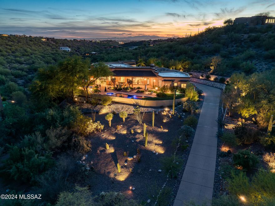 Set within the gated enclave of Rock Canyon Estates at Ventana Overlook, this remarkable single-level residence at 5043 N Marlin Canyon offers a rare combination of scale, privacy, and refined desert living. Positioned on more than 1.5 acres of manicured grounds, the home spans approximately 6,654 square feet and captures sweeping mountain views that create a constant connection to the surrounding landscape. The thoughtfully designed interior features a step-free layout with expansive living spaces that feel both grand and welcoming. Formal living and dining areas are generously proportioned, ideal for elegant entertaining, while the expansive family room, located adjacent to the kitchen, creates a comfortable and inviting hub for everyday living. A beautifully updated (continued) chef's kitchen anchors the home, appointed with premium appliances, abundant prep space, and a large walk-in chef's pantry. Just beyond, a dedicated bar area with wine refrigeration and an ice maker enhances the home's social flow and hosting capabilities. The primary suite is a true retreat, offering exceptional privacy, dual walk-in closets, and a spa-inspired bathroom designed for relaxation. A convenient secondary laundry within the primary suite adds to the ease of daily living. All secondary bedrooms are generously sized and feature ensuite baths, providing comfort and privacy for family and guests alike. A large multipurpose room, ideal as a home office, game room, or fitness space, provides flexibility to adapt to changing needs. Additional interior features include secure wine storage, an app-based home automation and audio system, and multiple fireplaces that add warmth and ambiance, including one in the outdoor living area. Outdoor spaces are designed for resort-style enjoyment. The backyard showcases a PebbleTec pool and spa surrounded by professionally curated landscaping and dramatic lighting. A fully equipped outdoor kitchen with built-in grilling stations and dual Green Egg cookers invites memorable al fresco gatherings, while the rooftop observation deck offers panoramic, 360-degree views, perfect for sunset entertaining or quiet reflection. Completing the property are modern, efficiency-minded amenities, including a fully owned solar system, a five-car garage with extensive storage, and an electric vehicle charging station. Located in the heart of the Catalina Foothills, the home enjoys close proximity, just minutes away, to acclaimed dining, shopping, golf, hiking, and luxury resorts. This exceptional estate delivers an elevated lifestyle defined by comfort, sophistication, and natural beauty, and offering that must be experienced to be fully appreciated.