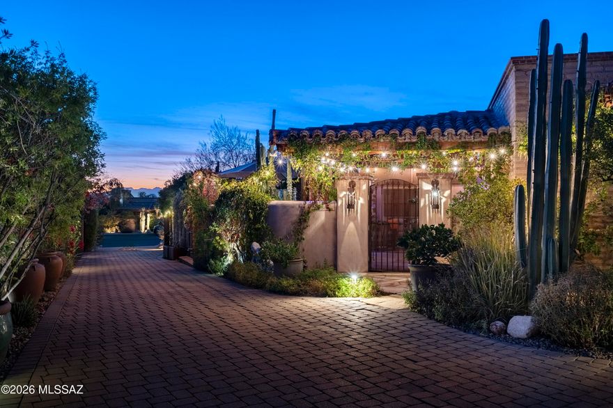 Conceived as an intimate dialogue between land, craft, and time, this authentic mud adobe residence is a quiet manifesto of place. Designed and built by James Gray of Stellar Gray Fine Homes, the home rests behind private gates within Adobes De La Vista, a rare enclave of 7 Adobe residences set in the heart of the Catalina Foothills. At 2,639 square feet with 3 bedrooms and 3 baths, the property unfolds as a composed sequence of spaces where architecture feels shaped rather than imposed, emerging naturally from the desert floor. The walls, formed from 16 inch thick stabilized mud adobe, give the home its unmistakable presence and deep sense of permanence. Their mass tempers light and heat, creating interiors that feel calm, grounded, and protective. Plaster surfaces soften the geometry, while stone walls built from rocks gathered on site root the architecture firmly in its surroundings. Antique columns sourced from India introduce a subtle global patina, standing as quiet witnesses to centuries of craftsmanship and lending the home a sense of lived history.

At the heart of the residence, the great room gathers living room, dining room, and kitchen into a single, fluid volume. This space feels generous yet restrained, where proportion and material guide the experience rather than ornament. Knotty alder cabinetry brings warmth and texture to the kitchen, its natural grain echoing the organic character of the adobe walls and concrete countertops, providing tactile surfaces reinforcing the honesty of the architecture. Light moves gently across the room throughout the day, reinforcing the feeling that time itself is an essential design element.

To the north, the great room opens seamlessly into a sunroom that acts as a luminous threshold between inside and out. Beyond, the north patio reveals an atmosphere reminiscent of San Miguel De Allende - intimate, layered, and quietly celebratory. Here, the architecture encourages pause and reflection, with framed views and shaded edges that invite long afternoons and unhurried evenings.

The south facing front courtyard offers a contrasting yet complementary experience. A covered veranda defines the space, creating a sheltered outdoor room that opens directly onto a built-in therapeutic spa. This courtyard serves as both arrival and retreat, a place where water, shade, and adobe walls converge to create a deeply personal sanctuary. Gardens weave throughout the property, offering paths to meander and moments of discovery, reinforcing the idea that this home is not simply occupied, but experienced.

Completing the narrative is an owned EnPhase solar system that works in quiet harmony with the thermal mass of the adobe construction. The thick earthen walls naturally moderate interior temperatures, absorbing warmth during the day and releasing it slowly as evening falls, while solar energy supports efficient and sustainable living. Together, these elements create a residence that feels timeless yet forward thinking, where comfort, responsibility, and beauty exist in effortless balance.