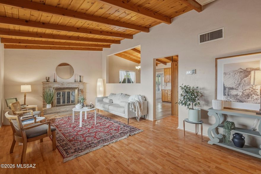 This desert retreat is a gardener's paradise. Abundant natural light floods the home allowing the pitched beamed ceiling to shine. The warmth of the wood provides a cozy ambience and a cohesion to every room. Warm and inviting with impeccably preserved midcentury charm that seamlessly blends modern touches. Featuring a stacked sandstone wood burning fireplace in the living room and beautiful knotty pine kitchen cabinetry with updated quartz countertops and newer stainless-steel appliances. Off the kitchen is the sunroom, a plant paradise with wall-to-wall windows, perfect for a second living room or an office. 

The expansive primary bedroom offers a large walk-in closet as well as a second closet, a seating area and an ensuite. The guest bathroom couldn't be more charming with pink and brown tile, knotty pine cabinetry and pitched beamed ceilings, in mint condition. The yard offers two fenced areas with fruit trees, herbs, produce, and a cactus garden. Walking distance to The Loop, Hop Shop, Brandi Fenton Park and the Botanical Gardens.   Come check out the midcentury charm for yourself!