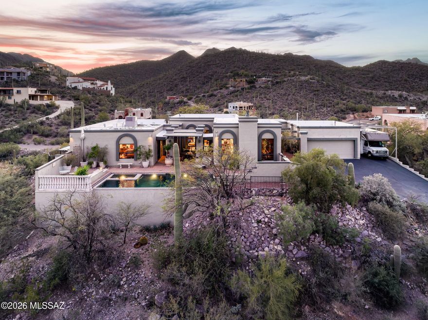 Perched atop a private hilltop cul-de-sac on an expansive 0.8 acre lot, this exceptional 3,201-square-foot custom residence captures breathtaking 360° city and mountain views. Offering 3 bedrooms plus a versatile bonus room and 3 bathrooms, the home blends privacy, superior craftsmanship, and convenient access to I-10, downtown Tucson, premier local attractions, and nearby hiking and biking trails.
A gated courtyard entry sets the tone for the resort-inspired backyard, where a stunning 15' x 30' faux-edge pool and spa overlook the Tucson valley. Designed for year-round enjoyment, the pool features a PebbleTec® black marble finish, in-floor cleaning system, solar and gas heating, automatic cover, custom water-wall feature, and a poolside gas fire pit. An outdoor shower with hot water enhances the experience. Additional exterior highlights include shaded RV/boat parking (12' wide x 11'4"+ high clearance), two secure dog areas, and a 6-zone irrigation system for effortless landscape care.
Inside, timeless finishes and quality details shine throughout. A French double-door entry welcomes you into living spaces defined by soaring 11-foot ceilings with exposed wood beams in the great room, living room, and sunroom. Cerdomus Kairos porcelain tile laid in a Versailles pattern is complemented by 8" tile baseboards and porcelain door casements. Triple-pane skylights bathe the home in natural light, while hand-troweled walls and curated designer finishes add warmth and refinement. Solid knotty alder interior doors, DuraSupreme Crestwood all-plywood cabinetry, and abundant built-in storage showcase the home's elevated craftsmanship.
The great room is anchored by a gas fireplace with a custom precast concrete mantel and dramatic floor-to-ceiling surround. A dedicated bonus room features extensive knotty alder built-ins, ideal for working from home. The spacious 16' x 18' primary suite offers direct pool access and a spa-like bath complete with a Thermasol steam shower, quartz countertops, and custom cabinetry.
Designed for both entertaining and everyday living, the kitchen features 30" deep rustic cherry cabinetry, Verde Bellagio granite countertops, a full travertine backsplash, roll-out drawers, in-cabinet lighting, double trash/recycle, a built-in desk area, and stainless-steel appliances. 
Extensive system upgrades provide peace of mind, including whole-house electrical and plumbing updates, two newer HVAC systems, a newer gas water heater, spray polyurethane foam roof (recoated February 2026), water softener, central vacuum, structured wiring, hard-wired security with CCTV, and whole-house A/V integration.
With no HOA, panoramic views, and resort-style amenities, this thoughtfully upgraded hilltop estate presents a rare opportunity to enjoy luxury desert living at its finest.