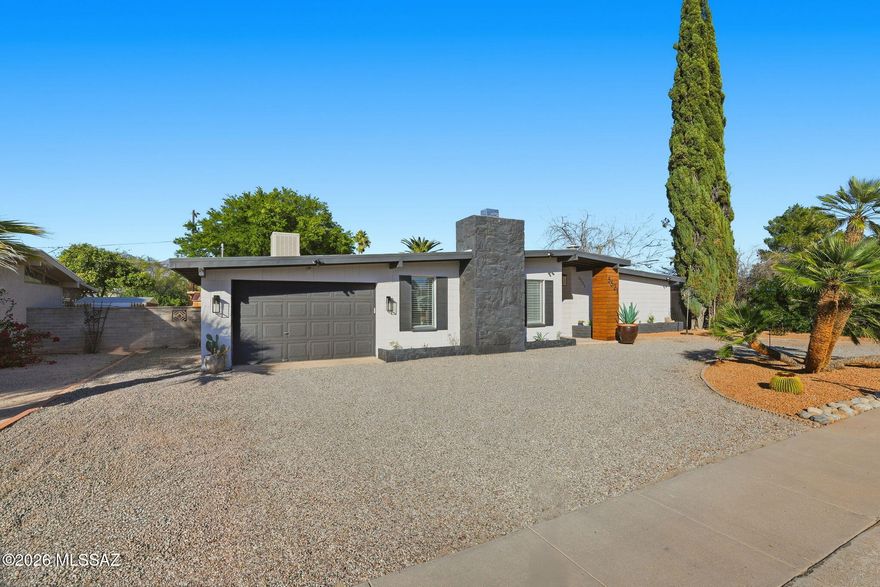 Stunning remodeled home on a large lot with modern style and abundant light. Vaulted ceilings, wood-look floors, recessed lighting, and skylight create an open, airy feel. Great room with exposed beams and stone fireplace, formal dining flows to the covered patio. Chef's kitchen with beautiful modern cabinets, granite counters, subway tile backsplash, center island, and stainless appliances. One bedroom with corner fireplace and private access. Serene backyard with RV hookup, carport, storage, and mountain views. Close to TMC, Pima Medical, Fort Lowell Park, shopping, and major employers.