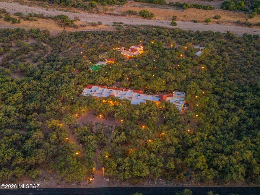 An extraordinary Tanque Verde estate: melding old world craftsmanship, French ambiance, and distinctive outdoor amenities. Gated approach leads to this elegant estate, complete with guest house, carriage apartment, over 11,000 sq. ft of living area.  Brick pathways wind through shaded gardens,  Parisian-inspired lampposts illuminate the landscape, and tranquil ponds and waterways reflect the sky. The grounds feel private and serene. Architectural details of this home are reminiscent of a Country French Chateau, from crystal chandeliers to elegant moldings. The main residence offers high ceilings, generous windows, and a flowing layout that contribute to an elegant yet welcoming interior. Living spaces are designed for comfort and versatility, *see additional comments* allowing for refined entertainment or as a quiet retreat. The kitchen's scale and function support daily living as well as elevated hosting. The outdoor features are exceptional: Mesquite shaded pathways meander through extraordinary park-like setting, complete with charming water gardens, fanciful footpaths, numerous fountains and statuary. A 1,000 sq ft greenhouse provides an impressive venue for year-round growing and botanical pursuits. The pool and spa area offer a relaxing backdrop framed by the property's natural beauty. Five garage spaces, lift, double carports, and 42'x 21' workshop/studio. The two additional living structures provide flexibility for guests, including 3393 sq ft. guest house, and studio carriage apt will not disappoint.  Every element has been planned to enhance both beauty and practicality across this estate. A rare opportunity to own a substantial property defined by its presence, acreage, and character.