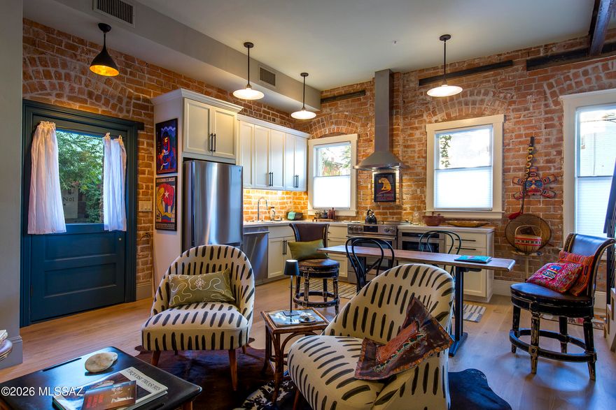 The historic Glenwood Hotel, c.1908, has been thoughtfully reimagined as a bespoke condominium building with just six residences. This home is packed with charm, quality, and modern finishes that complement the building's original architectural character.
Exposed brick anchors the open kitchen, creating a rich backdrop for custom wood cabinetry and modern finishes, while hardwood floors bring warmth to the main living space. The lower level includes a guest bath and upstairs an entirely private primary bedroom suite with heated bathroom flooring, a custom floating vanity, high-end fixtures, and a restored clawfoot tub.
The finished basement adds another remarkable layer of history, with walls constructed from volcanic rock quarried from the base of A-Mountain--an enduring connection to Tucson's early building traditions. All mechanical, plumbing, and electrical systems were replaced during an extensive 2024 restoration.