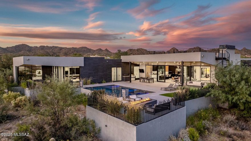 Modern luxury and integrated technology define this home, designed by renowned architect Marc Soloway with interiors by Designs by Priya. Located in Stone Canyon's premier guard-gated community, the property offers mountain views, unobstructed sunsets, and backs to preserved desert for privacy. A pivot front door opens to a streamlined floor plan with tall ceilings, 24x48 Italian tile, and a full glass wall overlooking the resort-style backyard. Western multi-slide doors create a true indoor-outdoor layout. The kitchen features a quartz waterfall island, Sub-Zero, Wolf, and Dacor appliances, a built-in Wolf coffee maker, dual sinks, a hidden walk-in pantry, white-oak accents, and a Sub-Zero wine column. T he primary suite includes floor-to-ceiling glass, a spa-inspired bath with black lavastone shower tile, floating vanities with LED mirrors, and a California Closets wardrobe. Secondary baths continue the same elevated detailing with floating vanities and full-height tile. The home is fully automated with a Control4 system managing audio, cameras, automatic shades, the cinema room, lighting, and more. Hallway lighting is upgraded to gallery-style fixtures. The cinema room includes built-in surround sound, an automatic projector, blackout shades, and a dedicated IT closet. Outdoor features include a saltwater pool and spa, view fencing, bar seating, and a Lynx Sedona grill. A custom metal spiral staircase leads to the rooftop deck for star-gazing, city light views, and sunset watching. A modern, well-built home with high-level finishes and a prime Stone Canyon setting.