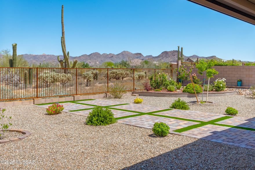Beautifully positioned in gated Preserve at Twin Peaks, this nearly new Lennar-built home offers the perfect blend of privacy, mountain views, modern comfort & several upgrades. Set on a premium 0.24-acre lot with no rear neighbors, this 4BR, 2½BA, single-story home features 2,598sf of open-concept living & extended 3-car garage. High ceilings & bright, open great room are complemented by dramatic center-opening sliding glass doors, creating seamless indoor-outdoor living. The gourmet kitchen is designed for gathering & entertaining, featuring granite countertops, upgraded cabinetry, stainless appliances, spacious pantry & oversized island. The owner's suite serves as a private retreat with patio access, dual walk-in closets & upgraded bath. Additional bedrooms offer flexibility for guest office space or multi-generational living. The backyard is fully improved with artificial turf, desert landscaping, covered patio space and view fencing, all set against peaceful desert surroundings with mountain and sunset views. The space is primarily finished in decorative gravel, complemented by a geometric layout of large paver pads separated by strips of green turf, creating a visually appealing grid pattern that's ideal for outdoor seating or entertaining areas. With over $90,000 in upgrades including backyard landscaping, patio shades, interior paint, water treatment system, window coverings, and added features throughout this home offers the benefits of new construction without the wait. Conveniently located near Twin Peaks, shopping, dining, parks, and schools, this home delivers the best of Northwest Tucson and Marana living in a secure and desirable gated community.