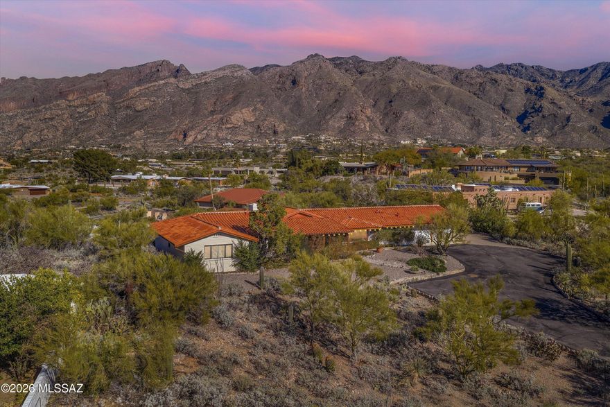 Perched on a coveted ridge in Skyline Bel Air Estates, this classic Catalina Foothills residence captures sweeping, unobstructed Catalina Mountain views and a sense of elevation that defines true Foothills living. Positioned noticeably above surrounding properties, the home enjoys panoramic sight lines, dramatic sunsets, and remarkable natural light throughout the day.
Built in 1968 with solid slump-block construction, the home reflects the enduring quality and authentic character that made the Foothills famous. These substantial walls provide natural thermal efficiency, durability, and timeless architectural appeal rarely found in newer construction.
Inside, approximately 2,869 square feet of thoughtfully designed living space includes expansive windows, generous living and dining areas ideal for entertaining, and comfortable separation between living and bedroom wings. Designed to capture the surrounding mountain scenery, the main living area offers generous scale and a layout that feels open and inviting. The spacious living room is highlighted by a fireplace, cathedral-style vaulted ceilings with exposed beams, and expansive windows that frame the Catalina Mountains while filling the space with natural light.
The kitchen offers abundant cabinetry, generous counter space, stainless appliances, and a practical layout that connects naturally to both casual and formal dining areas. An eat-in breakfast nook and built-in desk/workstation provide flexibility for everyday living, while the formal dining area enjoys views of the city, creating a memorable setting for gatherings and evening meals.
The bedroom wing provides separation and flexibility, including a spacious primary suite with mountain views, along with well-proportioned secondary bedrooms suitable for guests, family, or a home office.
Outdoor living is a highlight of the property. A kidney-shaped pool is positioned to capture the mountain backdrop, surrounded by expansive flagstone patios, multiple seating areas, and mature desert landscaping that blends seamlessly with the natural environment. Established saguaros, palo verde, and desert vegetation create texture, scale, and a sense of permanence that cannot be replicated in newer landscapes. A screened porch provides additional year-round outdoor living space ideal for morning coffee, evening gatherings, or enjoying Tucson's monsoon skies.
The property includes a two-car garage as well as a two-car carport, offering flexible covered parking and additional space for vehicles or guests.
Skyline Bel Air Estates is one of the Catalina Foothills' most established and desirable neighborhoods, known for its varied elevations, distinctive homes, and proximity to Tucson's best amenities. La Encantada's premier shopping and dining, world-class hiking in Sabino Canyon and Ventana Canyon, and the highly regarded Catalina Foothills School District are all just minutes away.
Ridge-top properties of this caliber rarely become available. With panoramic mountain views, authentic Foothills architecture, mature desert landscaping, and a setting defined by elevation and outlook, this home offers a rare opportunity to own a timeless piece of the Catalina Foothills lifestyle.