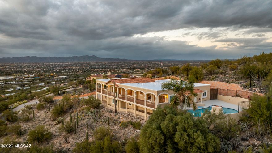 Welcome to The Arches at Pusch Ridge--an architecturally distinctive hillside residence where panoramic views, flexible living, and exceptional privacy come together in one of Oro Valley's most dramatic settings. Perched high against the backdrop of Pusch Ridge, this home captures extraordinary unobstructed views stretching from downtown Tucson to Picacho Peak. The 92-foot balcony--one of the home's most defining features--offers front-row seating for spectacular sunsets across the Tucson and Tortolita Mountains. To the rear, resort-style outdoor living unfolds with a pool, spa, outdoor fireplace, and multiple gathering spaces framed by breathtaking Catalina Mountain views. Whether enjoying sunrise over the Catalinas or sunset to the west, every outdoor space was designed to maximize the surrounding beauty. Inside, walls of windows fill the formal living and dining areas with natural light and ever-changing desert scenery. The kitchen features GE Monogram appliances and opens seamlessly to the main living spaces, creating ideal flow for both everyday living and entertaining. The privately positioned primary suite offers direct balcony access, dual vanities, two walk-in closets, and stunning surrounding views. Two additional bedrooms, baths, and the laundry room are also located on the main level. The lower level offers exceptional flexibility for multigenerational living, guests, or a private retreat with its own living area, kitchenette, bedroom, bath, laundry, separate patio, private entrance, and single-bay garage with additional storage. Pre-inspected and meticulously maintained, this home reflects true pride of ownership throughout. Its elevated positioning is what creates the commanding views that make this property unforgettable--a rare opportunity where architecture, scale, and setting align beautifully.