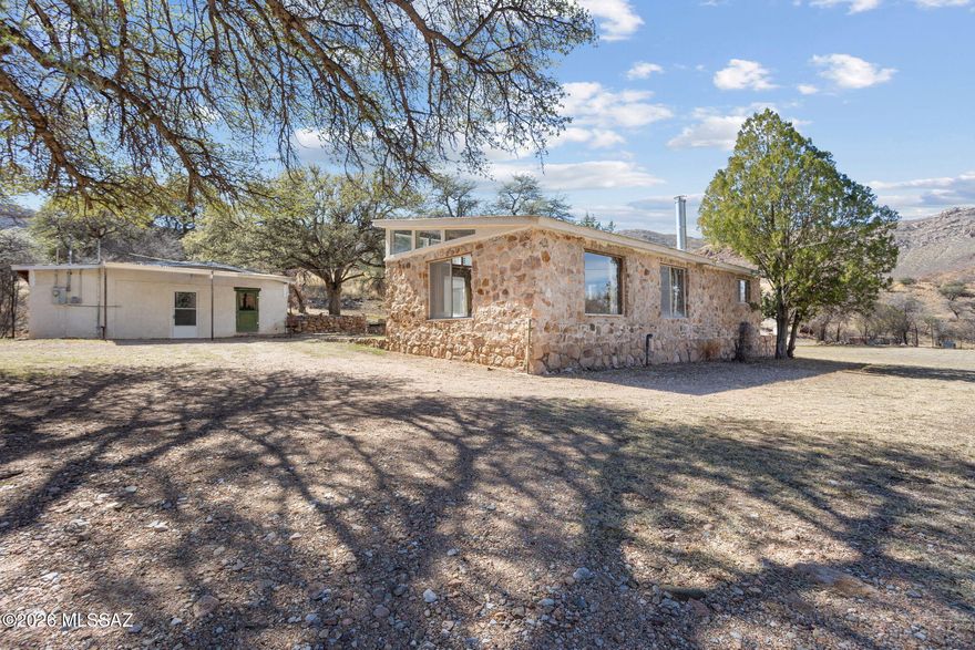 Nestled among the breathtaking Mule Mountains just five miles west of charming Bisbee, this magnificent 168-acre historic mountain ranch is a rare and remarkable offering that captures the timeless spirit of the American West. Known as Rocky Creek Ranch, the property greets you with a lush canopy of mature trees as you cross over Banning Creek and approach a stunning landscape featuring three seasonal creeks, dramatic waterfalls, towering rock formations, and rolling grassy meadows of Coastal Bermuda and native grasses that stretch across flat, undulating, and mountainous terrain alike. Two historic residences - the warmly updated Homestead House and the charming stone-walled Rock House, each with updated 200-amp electrical service - offer comfortable living accommodations totaling over 2,500 square feet, while a third structure, The Milk House, is in the process of being converted into an inviting studio home. The property is exceptionally well-equipped for agricultural and equestrian pursuits, featuring covered corrals, two livestock pens with a steel pipe squeeze chute, a large chicken pen, two windmills, four registered wells, two water storage tanks totaling 12,500 gallons, two septic systems, and surface water rights. Multiple outbuildings, a workshop, and covered parking for up to seven vehicles round out the working ranch infrastructure. Producing pomegranate bushes, walnut trees, and magnificent shade trees including Alligator Juniper, Black and White Oaks, and Mesquites add beauty and character throughout. With possible mineral rights, highway frontage on both sides of Highway 80, and roughly 2.5 linear miles of perimeter, this extraordinary property offers privacy, versatility, and an unmatched connection to the natural landscape of southeastern Arizona.