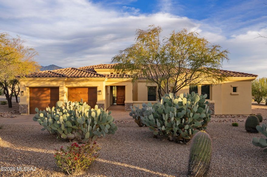 Nestled in the heart of Oro Valley in a small, gated enclave of luxury homes, your new home is a meticulously crafted Mediterranean masterpiece with Southwest touches that capture the very essence of Arizona luxury living. Resplendent with desert plantings, this property sits on a .83 acre lot with mountain views . From the moment you arrive, the winding paver driveway and striking rustic steel patina garage doors--serving both a two-car and a separate one-car garage--set a tone of sophisticated desert elegance. A small open courtyard and walkway lead into this 3351 square foot home flush with architectural interest. The interior unfolds with an opulent display of dramatic arches, soaring coffered ceilings, stately pillars, clerestory windows and graceful curves that define the expansive, open-concept living space--perfect for seamless entertaining. A stunning slate-finished fireplace serves as a warm focal point in the living room, while a breathtaking openable "wall of windows" dissolves the barrier between indoors and out, framing views of the pool and the majestic Catalina Mountains. The gourmet kitchen is beautifully finished and very functional, anchored by an abundance of rich Alder cabinetry and sweeping granite countertops that invite both conversation and culinary creativity. High-end stainless-steel appliances, a gas cooktop with a custom-framed tile backsplash, and a convenient adjacent butler's pantry ensure this space is as functional as it is beautiful. A casual nook overlooking the outdoor space is perfect for daily dining while a formal dining room with a large niche wall for art is ideal for dinner parties and holidays. The main living areas are serviced by a dramatic half-bath with a slate-faced vanity, glass vessel sink and a to-the-ceiling slate backsplash. Privacy and comfort abound across the four spacious bedrooms and 3.5 baths, including a primary retreat that feels like a private sanctuary. This oversized suite features a dedicated sitting area with mountain vistas, a spa-inspired bath with a deep soaking tub and a walk-in shower with intricate tile rope detailing, and a massive walk-in closet with built-ins to accommodate every need. Family members or guests also enjoy privacy in this home--one guest bedroom offers its own private ensuite bath, while two additional guest bedrooms share a full bath between them. Storage space is not an issue--alder cabinetry topped with granite in the laundry rooms, butler's pantry, pocket office and hallway provide ample room while the main two-car garage features a large built-in shelving unit. An additional one car garage could also be utilized as a seasonal gym or workshop (you could add a small mini-split and use year-round). The experience culminates in a resort-style backyard where a sparkling pool with a waterfall feature and a tanning deck fountain takes center stage. As evening falls, the desert sky is mirrored in the water while custom fire displays and a stone-finished outdoor bar and BBQ station create the ultimate environment for entertaining under the stars. Early morning or evening soaks in the separate hot tub soothes your muscles and relaxes your mind. A side yard area with Tortolita Mountain, open space and windmill views is a blank canvas for a permanent firepit, desert garden or whatever else you would like. Built by popular local luxury home builder Copper Canyon, this gently lived in home has also just had the exterior painted. Your new home is in the growing Tangerine corridor, only minutes from dining, shopping, golf and easy access to all Oro Valley, Marana and Tucson have to offer.