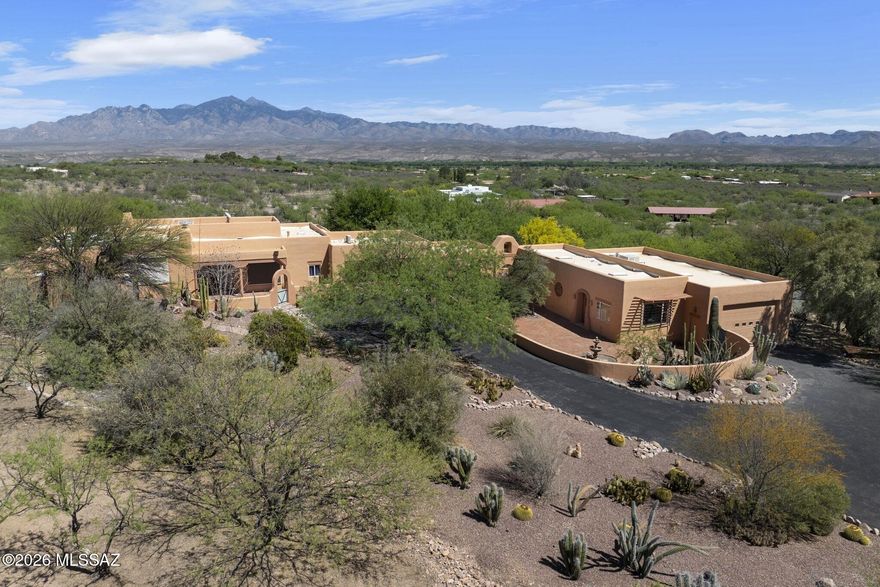Located above the artists' and bird watchers' paradise of Tubac, Arizona, this southwestern-style home is set on 4.1 acres, enough for horses or other livestock.  The entire property is enclosed by a combination of an artistically welded steel fence (40%) and a closely positioned barbed-wire fence (60%) that excludes cattle and javelina.  A rolling steel gate encloses the driveway, and two additional steel gates provide access along the perimeter.  The home features expansive open-sky views of the Santa Rita Mountains to the east and the Tumacacori Mountains to the west. In the main residence, oversize windows in the living room, foyer, and kitchen overlook a veranda with outside dining and seating areas.  The west-facing dining room looks over the courtyard entrance to the home. The large beamed living room and primary bedroom in the main house feature kiva-style fireplaces, one gas and the other wood-burning.  A nearly wall-sized picture window in the primary bedroom allows viewing of the more than 70 species of birds that come to feeders.  A large walk-in closet is a feature of the primary bathroom.  Most large windows in the home have outside electric rolling shades.  A two-car garage attached to the main house contains built-in shelves that provide ample storage.  An enclosed courtyard with mature landscaping faces the Santa Rita Mountains and surrounds a pool, spa, and grilling station.  Much of the acreage outside the walled areas has mature trees and other desert plants.  An attached casita with a kitchenette and full bath offers privacy and flexibility for guests or multi-generational households.  An attached but separate building contains two large rooms and a half-bath that are currently used as offices and art/music studios but can be used as bedrooms.  A center room with numerous cabinets, drawers, and shelves has been used as a darkroom.  An expansive RV garage and workshop are major features of this building.