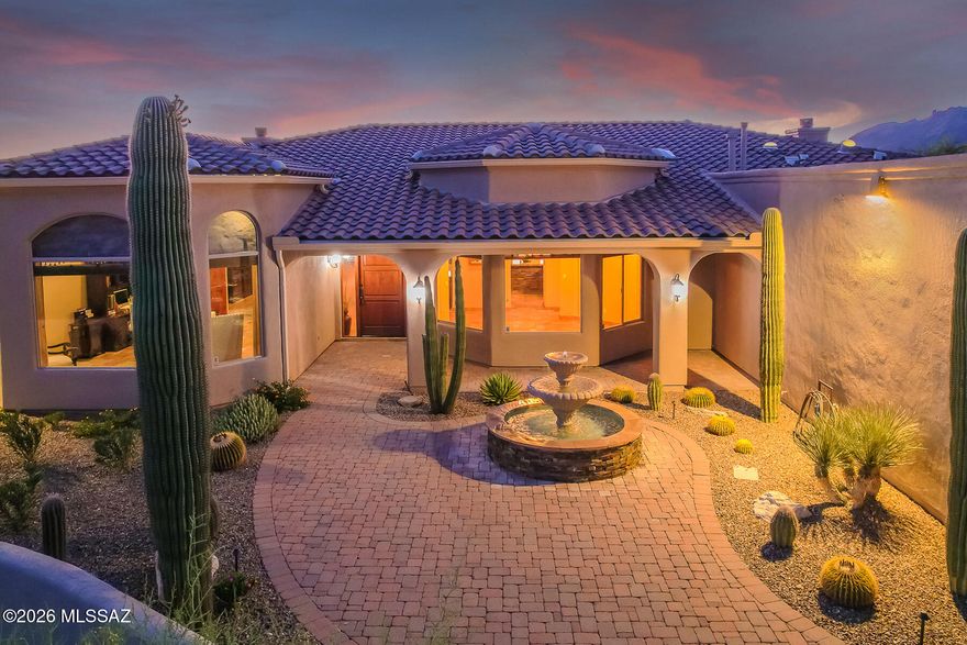 Set on 1.47 acres in La Buena Vida Estates, this 4,220 sq. ft. custom residence offers 4 bedrooms, 4 baths, den, a 3-car garage, and a beautifully private desert setting with mountain and sunset views. A gated courtyard entry with a refinished fountain sets the tone for the home's warm architectural character, including wood-beamed ceilings, travertine floors, alder doors, and expansive picture windows. The spacious kitchen features a large center island, chiseled granite counters, stainless steel appliances, a 5-burner gas cooktop, designer lighting, and generous storage. The primary suite includes a fireplace, large walk-in closet with custom built-ins, dual vanities, a soaking tub, and a refinished walk-in shower. Outdoor living is a highlight, with a massive covered patio, refinished tongue-and-groove ceiling, built-in BBQ, stone pathways, mature low-maintenance landscaping, private stone walls and fencing, and a refreshed pool and spa with glass tile. Recent improvements include exterior re-stucco and paint, roof resealing with warranty, refinished exterior doors, new bedroom carpeting, updated faucets, refinished cabinetry, custom window treatments, re-grouted and resealed showers, garage storage, epoxy garage flooring, security lighting, Ring doorbell, and security cameras. A beautifully maintained home offering privacy, scale, and classic Tucson living.