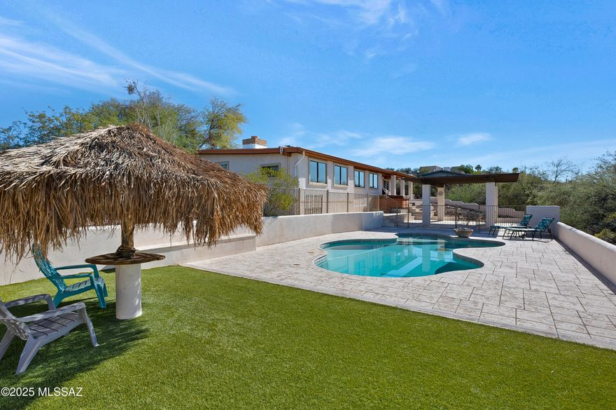 Discover the perfect blend of comfort, space, and Southwest lifestyle in this immaculately maintained 3-bedroom, 2-bath home set on 1.3+ acres with breathtaking, unobstructed views of the Tucson Mountains and no HOA. Privately positioned at the end of a quiet cul-de-sac, the property offers exceptional privacy, expansive outdoor living, and stunning west-facing sunsets that paint the desert sky each evening. An extensive paver driveway welcomes you home and sets the tone for the thoughtful design and pride of ownership found throughout. Inside, a bright and open great-room layout seamlessly connects the living area, kitchen, and dining space-each intentionally positioned to capture mountain views, natural light, and the surrounding desert beauty. The dining area is a true highlight, offering panoramic vistas of the westside mountains and frequent sightings of local wildlife roaming the natural landscape beyond the backyard. The split-floor plan enhances privacy, with the primary suite thoughtfully separated from the guest bedrooms. The expansive 19' x 28' primary suite delivers a true retreat, featuring vaulted ceilings that create an airy, luxurious feel, direct patio access for easy indoor-outdoor living, and a large walk-in closet. Adjacent to the primary suite is a generously sized 17' x 14' bonus laundry/utility room, currently used for storage and laundry, with the flexibility to be converted into a fourth bedroom, office, or additional living space if desired. Major system upgrades provide peace of mind, including a newer roof and HVAC system (approximately 4 years old) and a water heater replaced just 3 years ago. Step outside and enjoy resort-style living with a sparkling pool and relaxing hot tub, perfectly positioned on the lower portion of the lot to take full advantage of Arizona's sunshine and open desert surroundings. The outdoor spaces are designed for low maintenance and maximum enjoyment, featuring artificial turf, generous yard areas on both the north and south sides of the home, and ample room to entertain, relax, or simply take in the views. The former garage has been converted into a versatile workshop and storage area, ideal for hobbies, tinkering, or creative projects, while a small additional garage structure offers exciting potential as a studio, workshop, or home office. Previously a strong-performing Airbnb, this property also presents an excellent opportunity for those seeking flexibility for personal use, investment, or multi-purpose living. With its combination of acreage, views, privacy, modern upgrades, and exceptional outdoor amenities, this one-of-a-kind Tucson property offers a rare opportunity to enjoy true desert living without compromise. Schedule your private showing today and experience the sunsets, serenity, and lifestyle this remarkable home has to offer.
