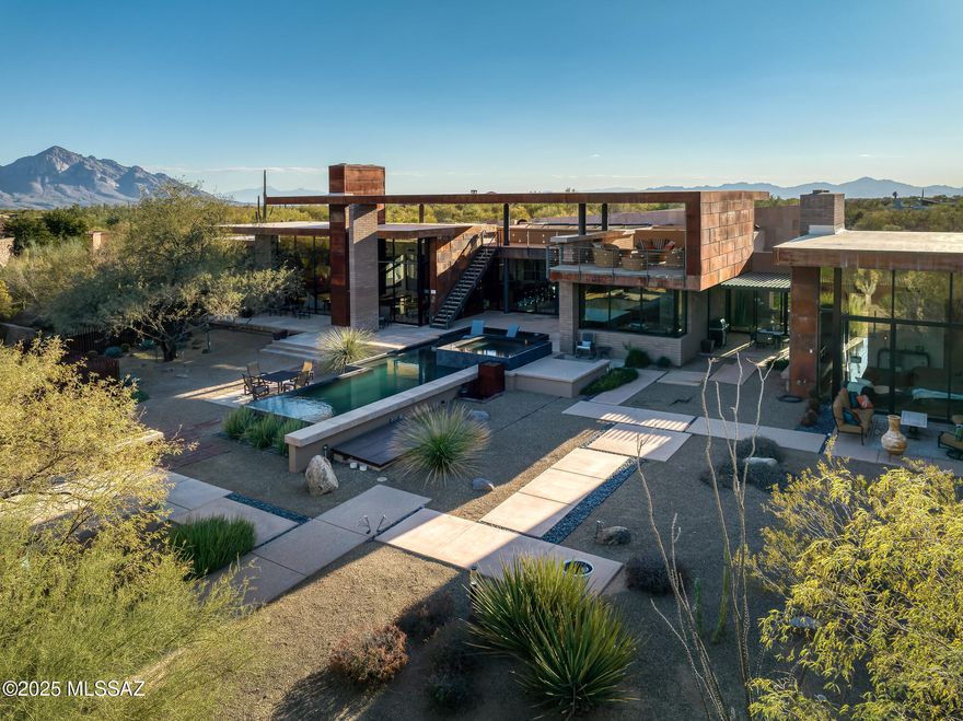 NEW PRICE! Welcome to a masterpiece of architectural brilliance at 474 W Tortolita Mountain Circle, a custom-built home nestled in the prestigious community of Stone Canyon. Designed by acclaimed architect Kevin Howard, this magnificent home offers a seamless fusion of luxury and modern aesthetics. Spanning nearly 6,000 square feet, the home showcases breathtaking views of the surrounding Catalina Mountains and the exclusive Stone Canyon Club's Hole #2, an exquisite Jay Morrish design. As you enter this one of a kind treasure, you're greeted by expansive glass walls that blur the boundaries between indoor and outdoor living. These disappearing walls are intertwined with the use of exposed masonry walls and ceilings of wood, metal, block and brick.  Sabbia Limestone flooring flows effortlessly throughout, complemented by sandstone finish walls, honed black granite and high-end Hansgrohe fixtures that exude sophistication and style. The open-concept design of numerous living areas that flow seamlessly together include a large living room which wraps into a family room and a kitchen designed for chef's featuring top-of-the-line Dacor and Wolf appliances, paired with a Subzero refrigerator, prep sink. warming drawer, commercial ice maker and oversized island. The exquisite master suite provides a sanctuary of luxury with a glass bead fireplace, an en-suite bathroom with a sumptuous soaking tub, a large shower, and convenient his and her sinks, toilets, and closets - complete with a stackable washer and dryer for added convenience, the suite's design emphasizes both comfort and privacy. Additional living spaces include a sophisticated office ideal for remote work or personal projects. 2 more bedrooms with en-suites complete this perfect split bedroom floor plan.  The detached guest house is a haven of convenience and style containing a cozy seating area, TV, Murphy bed, refrigerator, microwave, and bath with walk-in shower - perfect for hosting guests in comfort and privacy. An architectural gem that harmonizes opulence with nature's beauty and an added touch of Zen - note the custom designed landscaping with numerous water features, rock gardens and stepping stones surrounding the breathtaking negative edge pool and spa crafted specifically in black tile & pebbles.  Be prepared to be in awe of the 7,754-square-foot rooftop deck done in sandstone & metal that features an outdoor fireplace and TV. (Seller has prepared the home perfectly for the new owners - listed here is just a few of the numerous upgrades such as 3 new high efficiency hvac systems, pool equipment and pentair integrated app system, one year termite warranty, roof completely recoated 2025, sandstone tile installed on roof deck, flagstone patios, complete new irrigation system, custom barrier fencing,  plus owner owned solar system just inspected by Solar Store.)