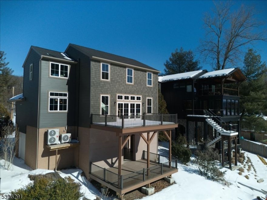 Stunning home on the Delaware River, nestled between the lovely river towns of Stockton and Frenchtown. Offering three levels of luxurious indoor and outdoor living, this residence makes the most of sweeping, unobstructed views up, down, and across the river. Completely rebuilt with exceptional craftsmanship, every detail reflects thoughtful design and connection to nature. Soothing tones and materials white oak floors, sage green kitchen cabinetry, chestnut tongue-and-groove ceilings, warm gold fixtures, and alabaster and spruce bath tiles create a seamless harmony with the surroundings. At ground level, a large sheltered area invites entertaining with space for an outdoor kitchen and a generous deck overlooking the water. A tall, deep garage provides ample room for a boat or jet skis. The main level features an open floor plan with a family room and gas fireplace set in a floor-to-ceiling stone hearth, dining area, and a chef's kitchen with a 6-burner Thor stove, stainless appliances, and an oversized quartz island. A full bath and a vaulted bedroom ideal as a den or office complete the floor.Upstairs, two bedrooms share a hall bath, while the primary suite boasts a spa-like ensuite with Carrara marble double vanity and a glass shower with bench. A bright laundry room and wood-paneled elevator add everyday ease. Perfectly situated for quiet riverfront living yet minutes from Stockton, Frenchtown, Bull's Island, and Delaware Canal State Park.