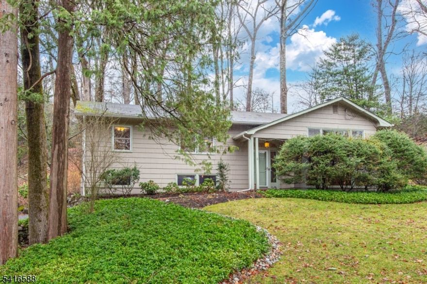 Nestled on a picturesque .70-acre lot in the coveted "Hill" section, this inviting home is a true retreat. Sunlit spaces, an open layout, and charming architectural details greet you from the moment you step inside. The expansive Living Room features parquet wood floors and a brick wood-burning fireplace, while the Dining Room boasts skylights, sliding glass doors to a stone patio, and a serene, private backyard perfect for relaxing or entertaining. The kitchen, adjacent to the Dining Room, offers ample cabinetry, a breakfast bar, and endless potential. The primary suite includes a full bath and walk-in closet, with two additional bedrooms sharing a hall bath. Bonus: hardwood floors are waiting to be uncovered beneath the carpet in 2 bedrooms! The lower level features an inviting Family Room with a second brick fireplace, a private office, a laundry/utility room, and a half bath. An oversized two-car garage with an electric car charger completes the home. Located in a peaceful neighborhood near The Tourne County Park, this property offers room to bring your vision to life, whether through simple updates, renovations, or an addition. Don't miss this Mountain Lakes gem!