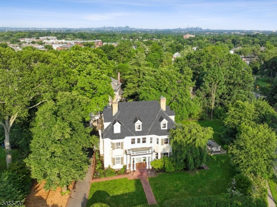 Welcome to a true architectural gem where history, craftsmanship, and location converge. Set on over 2/3 an acre just a few blocks from vibrant Downtown Montclair, this 1905 Colonial Revival stuns from the start with its Corinthian-columned front porch and original Dutch door, an elegant prelude to the timeless beauty within. Lovingly restored over the years, the home retains a remarkable array of period details: tiger oak floors, stained and leaded glass windows, working pocket doors and seven fireplaces, each with its own unique mantel - none more exquisite than the hand-carved oak surround in the gracious living room. The formal dining room, complete with its own hearth, sets the scene for unforgettable gatherings. With over seven bedrooms and five full baths, three of them en-suite, this home offers room to grow, create, and dream. With initial zoning approvals in place, the possibilities extend even further with the magnificent three-bay, cross-gabled, two-story carriage house at the rear.  It offers endless potential for additional living space, an art studio, a place to house your car collection and/or guest quarters. Just 0.7 miles to the Bay Street train station & steps to Montclair's beloved shops, restaurants, arts scene & farmers market, this one-of-a-kind property pairs the soul of an heirloom home with the convenience of city-suburban living. A rare and wonderful opportunity to become a steward of Montclair history.