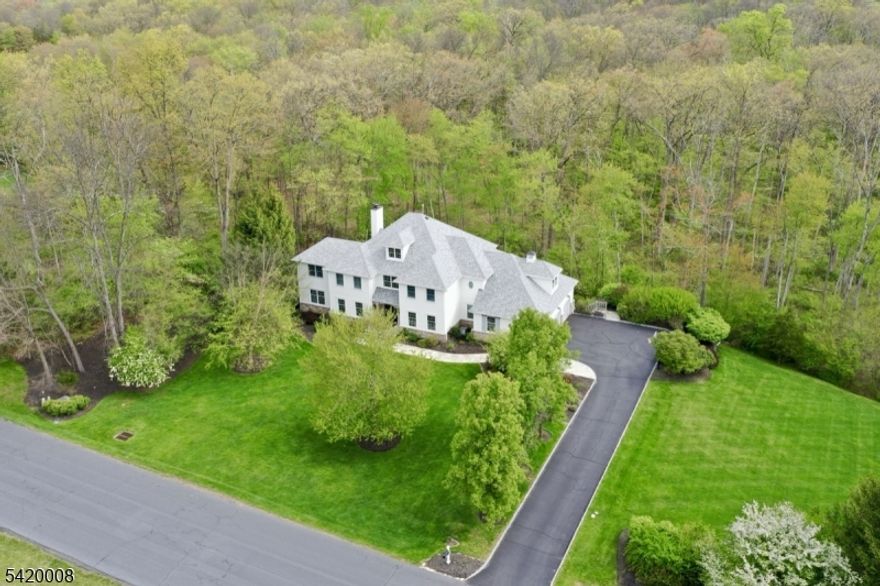Set on over seven acres of sweeping lawns and private wooded surroundings, this exceptional five bedroom, four full and one half bath residence offers a refined, design-forward aesthetic with resort-style living. Light-filled interiors feature clean lines, curated finishes, and designer lighting. The gourmet kitchen is outfitted with commercial grade appliances, custom cabinetry, and an expansive center island, opening to inviting gathering spaces for everyday living and entertaining. A richly appointed club-style family room with coffered ceiling and stone fireplace adds warmth and character, while marble baths and fresh neutral interiors create a crisp, modern feel. The luxurious primary suite offers a vaulted tray ceiling, two room layout, spa-like bath, and two walk-in closets. The walkout lower level is designed for entertaining and serves as a pool house, with lounge areas, bar space, full bath, fitness room, custom wine cellar, and a flexible fifth bedroom ideal as a guest suite or playroom. Outdoor living features a saltwater pool, expansive decking, and privacy. Recent updates include 2024 roof, front doors, gutters, plus renovated 3 car garage with epoxy floor and lower level in 2022. Truly move-in condition. Located in "The Hills" with access to pool, pickleball, tennis and fitness. Basking Ridge location with award winning schools, easy access to highways, airport, parks, and proximity to golf and equestrian facilities. Four flat screen TVs and built-in speakers.