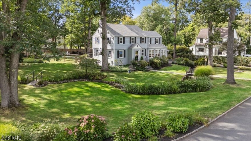 Welcome to this elegant Colonial, perfectly sited on a picturesque corner lot in one of Summit's most desirable neighborhoods. The front yard makes a memorable first impression with a charming creek, landscaped gardens, and three small bridges that add to the home's storybook appeal. Just minutes from downtown Summit, top-rated schools, and direct trains to NYC, this residence offers an unmatched blend of beauty and convenience. Inside, sunlight fills gracious living spaces with hardwood floors and timeless details. The living room with fireplace is warm and inviting, while the dining room flows into a sunlit enclosed porch. The kitchen is outfitted with granite counters, a center island, and SS appliances, opening to the premium, low maintanace Azek Deck and patio for easy entertaining. A spacious family room with sliding glass doors extends the living space outdoors. The backyard is an absolute retreat, complete with multiple patios, a dining deck, a fire-pit lounge, and mature trees providing both shade and privacy. Upstairs, the serene primary suite includes dual walk-in closets complemented by two additional oversized bedrooms filled with plenty of natural light and a full hall bath. The finished lower level offers a flexible room, office nook, and full bath. A laundry/mudroom and an oversized 2-car garage add convenience. With its one-of-a-kind setting, indoor-outdoor lifestyle, and Summit address, this home is a unique opportunity to own something truly special.