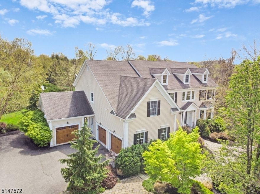 Encompassing 3 lush acres on a private drive near The Hills section of Basking Ridge, this Bocina-built Custom Colonial home offers an oasis just minutes away from transportation, schools and shopping. With over 5300 square feet of living space in addition to an 1800 square foot finished basement, this expansive floor plan offers a stylish and comfortable home for everyday living with multiple home office options. From the entry foyer, you enter into the formal dining room and living room with gas fireplace highlighted by custom moldings and millwork. The kitchen greets you with oversized center island perfect for entertaining. The kitchen features a walk-in pantry, stainless appliances and breakfast area which overlooks a sunken family room with coffered ceilings and wood burning stone fireplace. A wall of windows let in plenty of sunlight and provides a view of the lush serene outdoor space. The built in firepit and outdoor kitchen with granite countertops, grill and refrigerator is an entertainer's dream. The second floor, accessed by two staircases, consists of 5 bedrooms in all. The primary suite includes a sitting room for those quiet moments reading or working from home,  2 walk-in closets and en-suite bathroom with custom tilework. The additional 4 bedrooms and 2 bathrooms are configured into 2 Jack and Jill suites.The lower level with gleaming hardwood flooring includes a game room, entertainment area, gym, den, full bath, and a 300 plus bottle wine cellar.