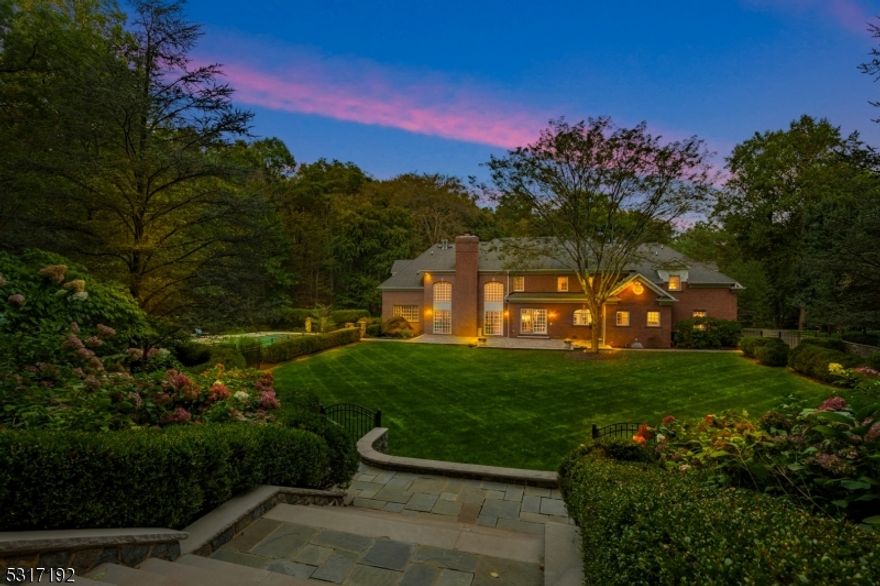 A property of incomparable grandeur and unparalleled luxury, 5 Cobblefield Drive is a Georgian colonial in Mendham, situated on meticulously landscaped grounds. Entered via a circular driveway with Belgium block curbing, this handsome custom-designed residence offers both sophistication and comfort.Upon entry, the two-story foyer impresses with its Palladian windows and curved staircases. The home's high ceilings, French doors, and panoramic windows accentuate the magnificent rooms, creating an inviting and light-filled atmosphere. Elegance is presented through raised-panel wainscoting, arched doorways, and fireplaces with marble surrounds.The gourmet kitchen is a chef's dream, featuring high-end appliances and a functional layout, perfect for entertaining. Adding to the home's versatility, a first-floor bedroom with a full bath provides additional convenience for guests. .The outdoor retreat offers a level rear yard, ideal for hosting gatherings or enjoying peaceful moments surrounded by nature. The expansive grounds also feature a concrete pool with a hot tub and tanning ledge, perfect for relaxation. A recently added generator ensures peace of mind and uninterrupted comfort. With a regal columned entry, cherry wood flooring, and bespoke details throughout, 5 Cobblefield Drive is a distinctive property offering luxury, charm, and the ultimate in privacy.