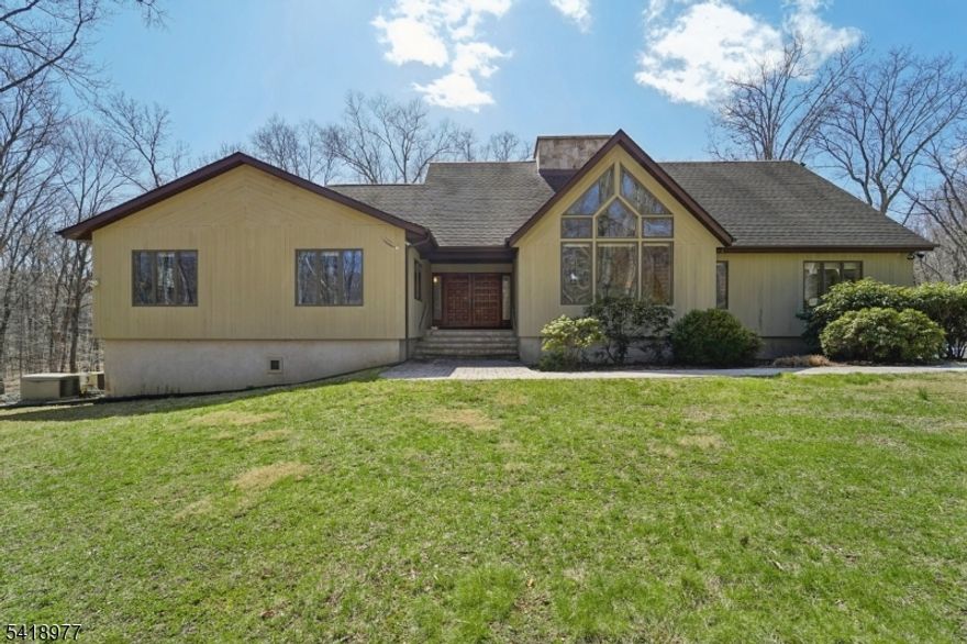 A winding, tree-lined drive sets the tone for this exceptional contemporary retreat set on 5.7 private acres backing to parkland in Chester Township. Thoughtfully maintained and move-in ready, this contemporary expanded ranch delivers single-floor living at its finest ? four spacious bedrooms, soaring ceilings, and walls of windows flood the open floor plan with natural light. The renovated kitchen features a large center island, country layout and eat-in kitchen perfect for entertaining, while the grand living and family rooms anchor the home's dramatic interior. A loft overlooks the main level and leads to a discreet ladder-access safe room ? a truly unique feature ideal for secure storage. The luxurious primary suite spans 26x18 with a stunning en-suite bath. Partially finished basement provides room to grow. Outside, enjoy a massive 38x13 deck, hot tub, and beautifully manicured yard. Car enthusiasts and hobbyists will appreciate the rare 5-car garage capacity plus a 12x24 outbuilding ? ideal for a workshop, collector vehicles, or additional storage. A whole-house natural gas auto-transfer generator adds year-round peace of mind. New gutters throughout. All furnishings available for purchase. Multi-zone heat and cooling, dual-sided wood-burning fireplace in living room and family room, private road setting. Minutes to top-rated W.M. Mendham schools. Extreme privacy, space, and one-of-a-kind features rarely found at this price.