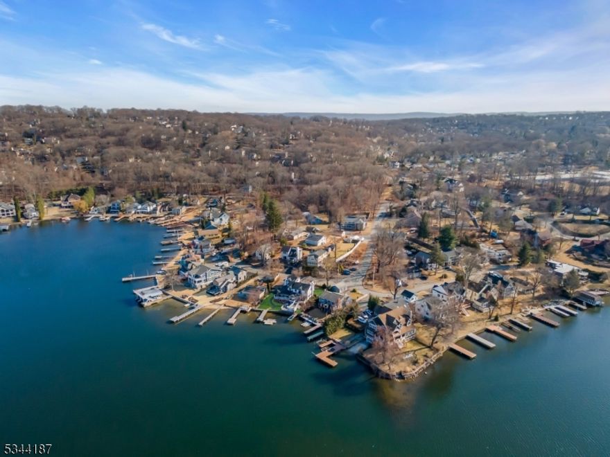 Welcome to an extraordinary lakefront retreat in the highly sought-after location! This stunning 3,500sqft home designed for seamless entertaining across 3 levels of luxury. From the moment you step inside, an open floor plan with gleaming hardwood floors draws you into the gourmet kitchen, featuring granite countertops, a spacious center island, a coffee & wine bar, & breathtaking waterfront views. The living & dining areas flow effortlessly into a sunroom, while a formal dining rm offers the option for a first-floor bedrm. A charming den with French doors overlooks the lake, creating the perfect home office or relaxation space.  The second floor boasts 3  bedrms, 2  full baths, a cozy loft with a decorative fireplace, & an additional loft ideal for an elevator conversion. The primary suite spans the back of the home, complete with stylish barn doors, walk-in closets, a spa-like bath & a private lakefront balcony.   The lower-level is an entertainer's dream, featuring a theater room, family and game rooms, a custom wet bar, a full bath, and a second laundry room. Step outside to a lakeside patio just feet from the water, complete with two docks. Enjoy outdoor living on the wraparound porch, upper lounge deck & sunken hot tub. A 2 car garage &  a finished fitness center in the 3 bay complete this incredible property.  City water, sewer, and natural gas in a prime commuter location, this level 100-ft lakefront lot is your dream home. start living your best lakefront life!