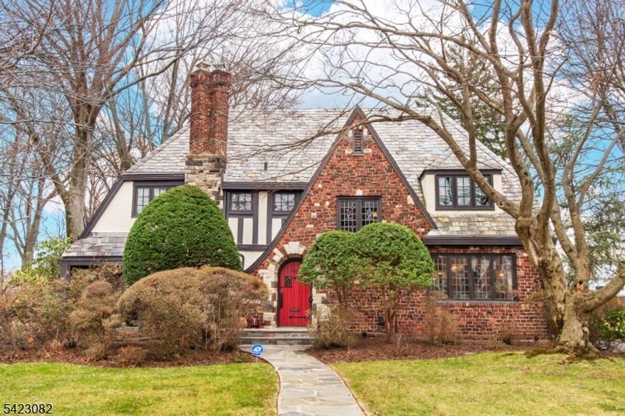 A timeless 1929 residence, meticulously maintained and thoughtfully upgraded to today's standards, offering 5 bedrooms and 3.5 baths with exceptional craftsmanship rarely found. A warm, inviting foyer introduces a home where original character blends seamlessly with refined modern finishes.Designed for both entertaining and everyday living, the first floor features a sunken formal living room with a dramatic 10-foot beamed ceiling, stained glass windows, and a gas fireplace. An oversized family room offers a second gathering space with its own fireplace and direct access to the bluestone patio. Updated Pella casement windows enhance efficiency and style throughout.The chef's kitchen is a standout, appointed with custom cabinetry, walk-in pantry, Sub-Zero and Wolf appliances, and premium finishes, flowing into a formal dining room ideal for hosting. A private office, along with a bedroom and full bath, provides flexibility for guests. Upstairs, the primary suite offers a private retreat with its own full bath, complemented by three additional bedrooms and a spacious hall bath. A finished basement adds versatility for recreation, fitness, or work-from-home needs.Set on a secluded 1/2-acre lot, outdoor living is elevated with a bluestone patio and fully equipped kitchen featuring a built-in BBQ, granite counters, beverage refrigerator, and sink. Ideally located with close proximity to shopping, transportation, and a walkable house of worship.